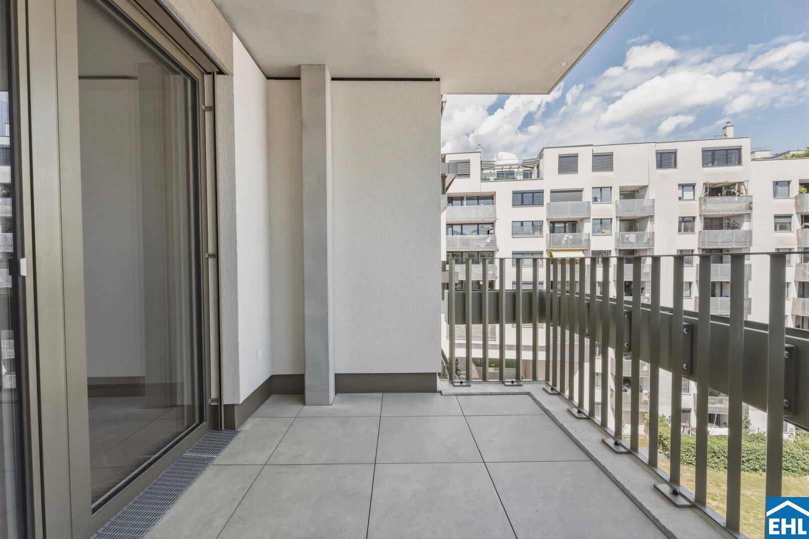 Geräumiger Balkon mit Fliesenboden und Blick auf die umliegenden Gebäude.