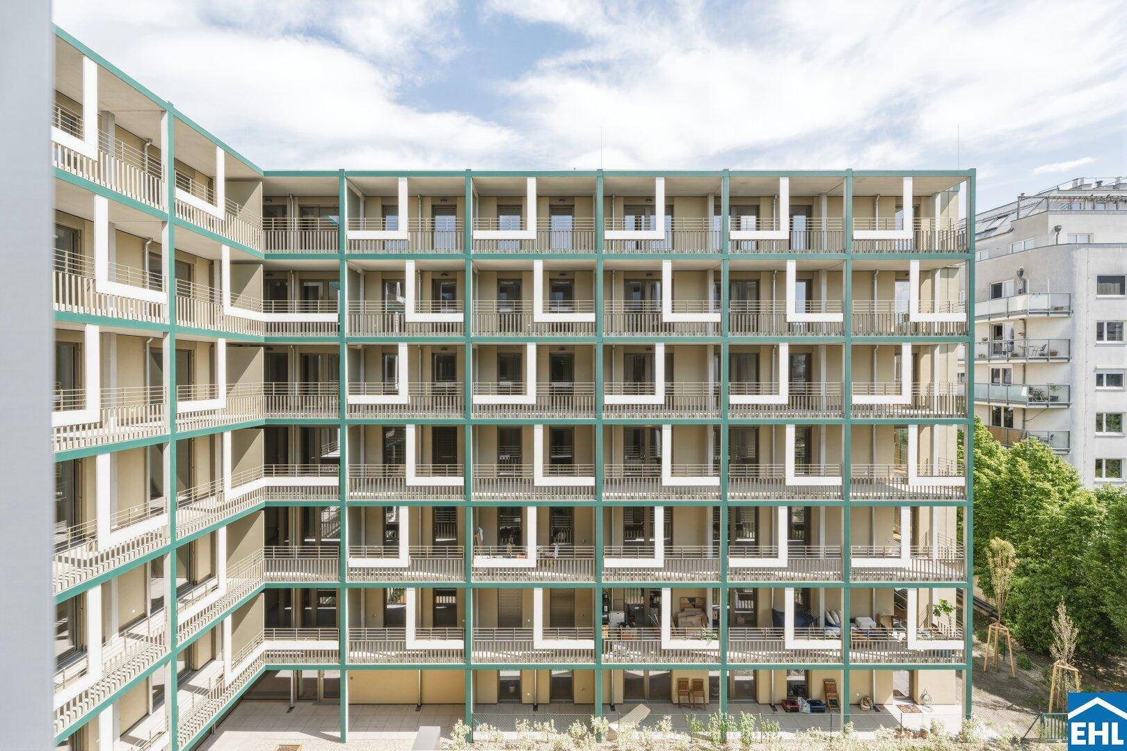Ansicht des modernen Wohnkomplexes mit zahlreichen Balkonen und grünen Akzenten im Innenhof.