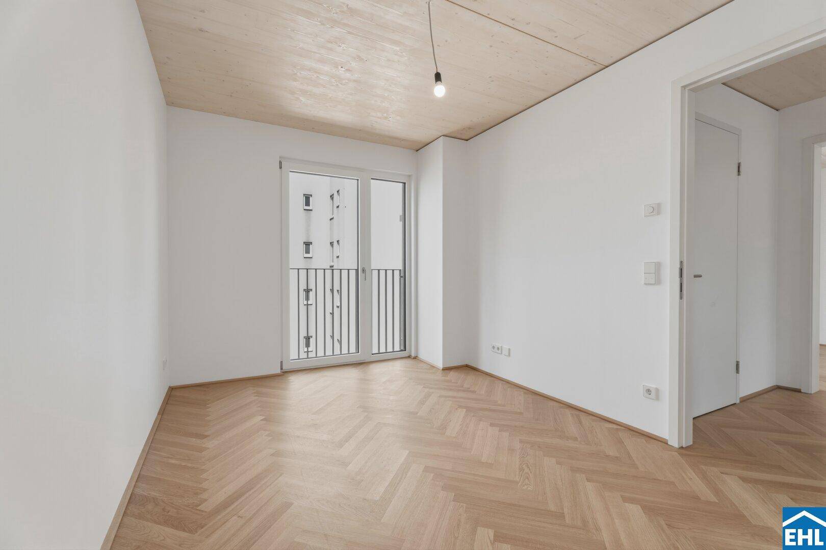 Modernes Schlafzimmer mit Fischgrätparkett und Zugang zu einem französischen Balkon, ideal für Stadtbewohner.