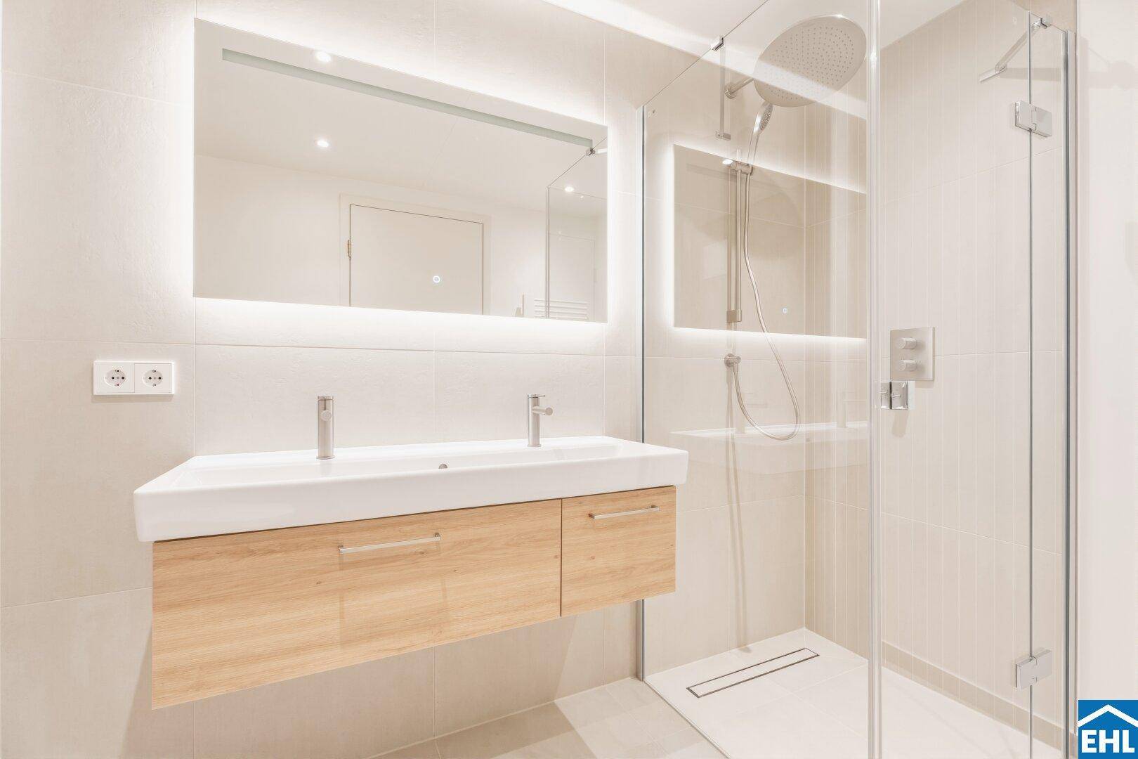 Elegantes Badezimmer mit Doppelwaschbecken, großer Spiegelfläche und begehbarer Dusche mit Regenduschkopf.