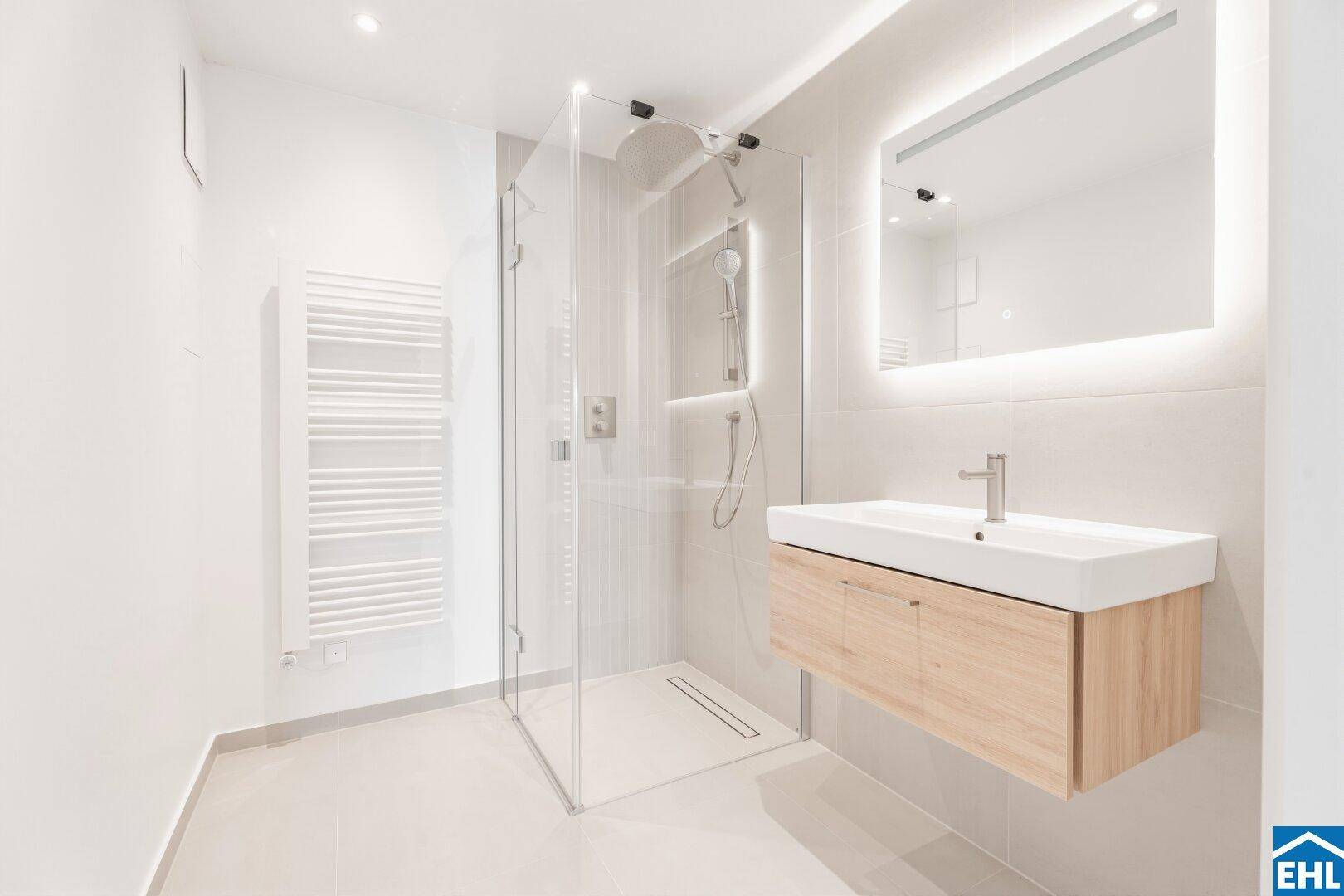 Modernes Badezimmer mit begehbarer Dusche, beheiztem Handtuchhalter und schwebendem Waschtisch.
