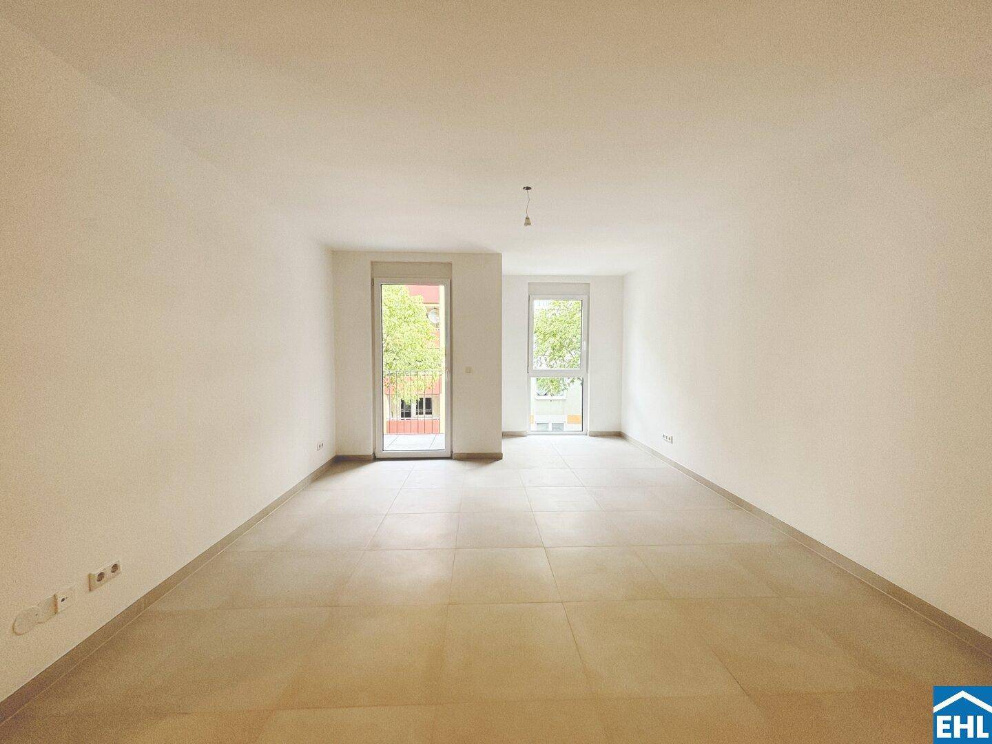 Geräumiges, helles Wohnzimmer mit Fliesenboden und Zugang zu einem französischen Balkon.