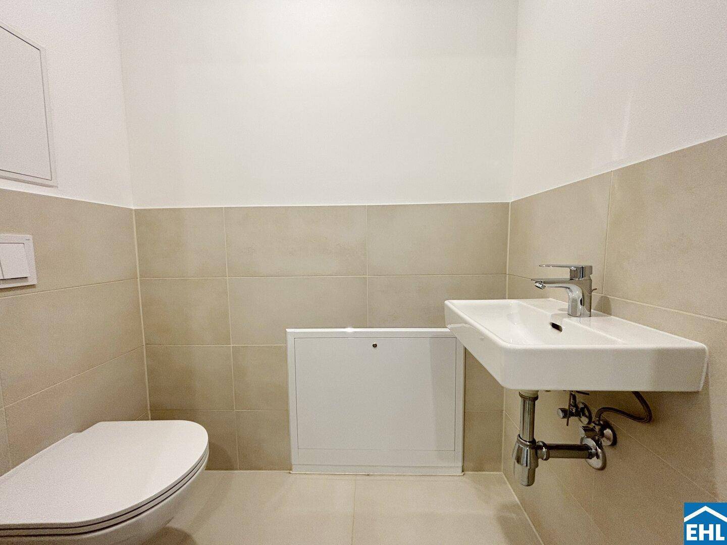 Modernes Gäste-WC mit Wand-WC und Waschbecken, hell gefliest.