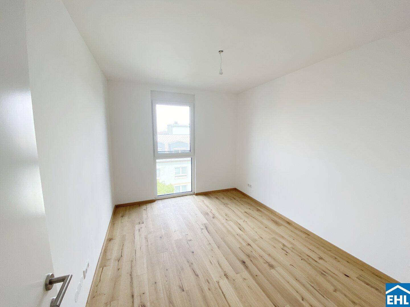 Helles Schlafzimmer mit neuem Holzboden und großem Fenster, bereit zur individuellen Gestaltung.