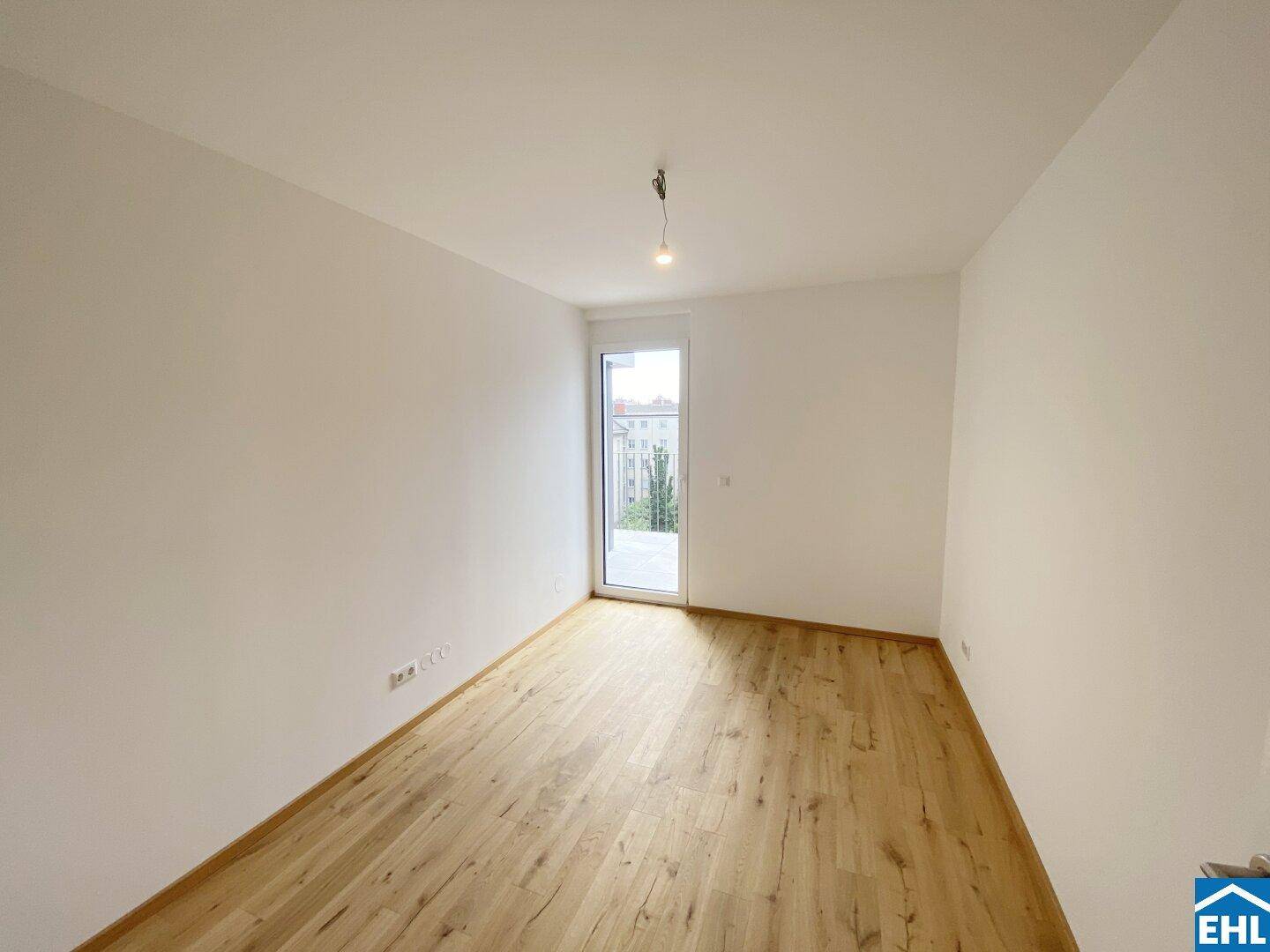 Freundliches Zimmer mit hellem Holzfußboden und Zugang zu einem kleinen Außenbereich.