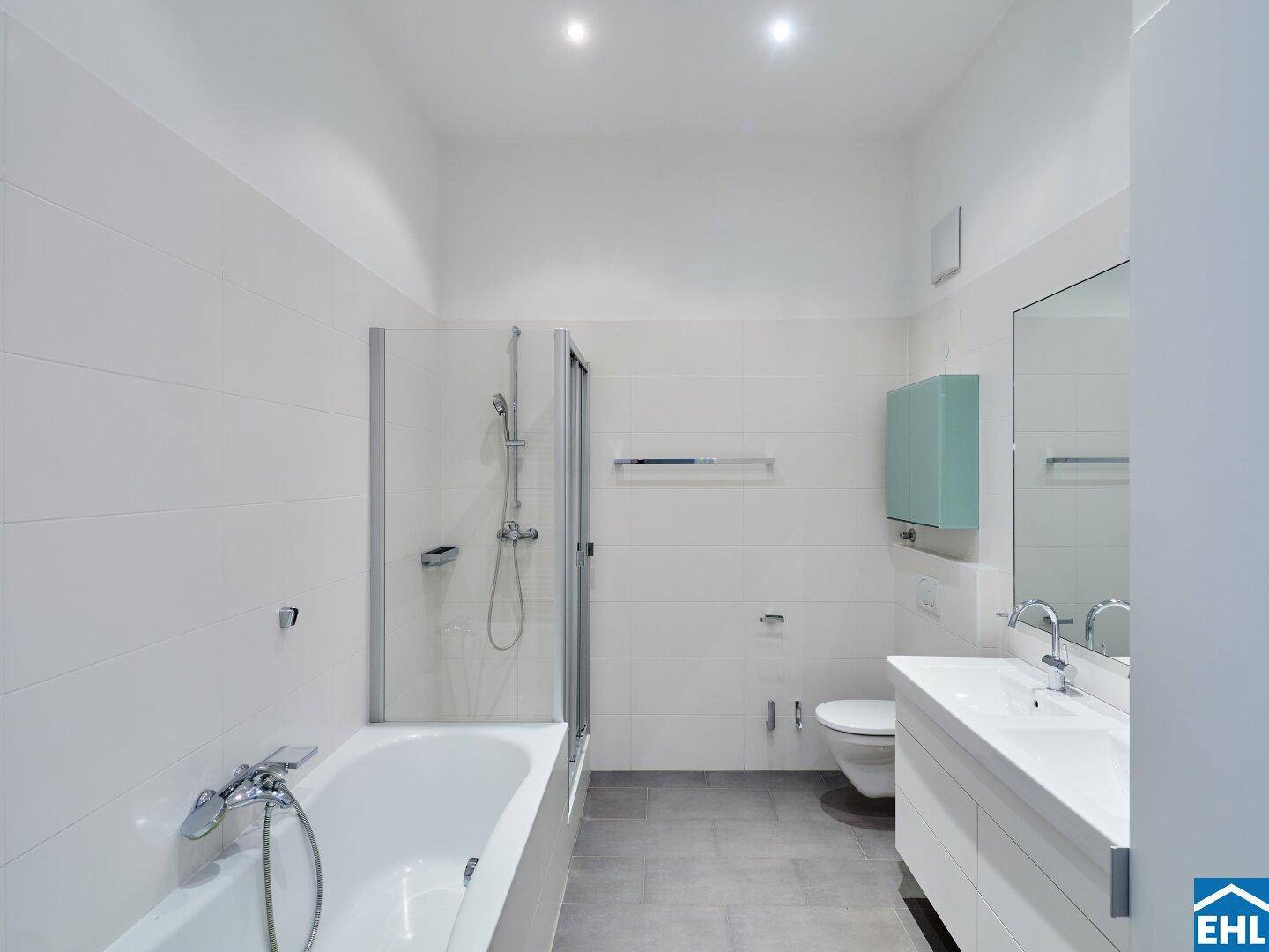Helles Badezimmer mit Badewanne, Duschkabine und modernem Waschtisch.
