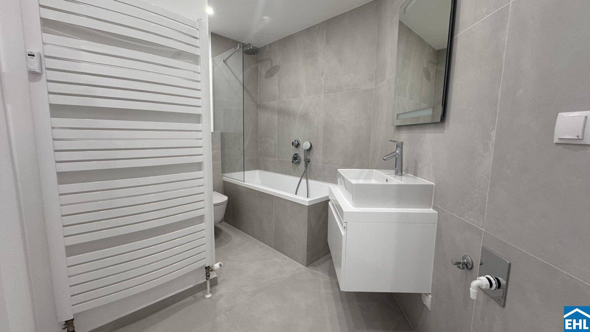 Zeitgemäßes Badezimmer mit Badewanne, Duschabtrennung und elegantem Waschtisch.