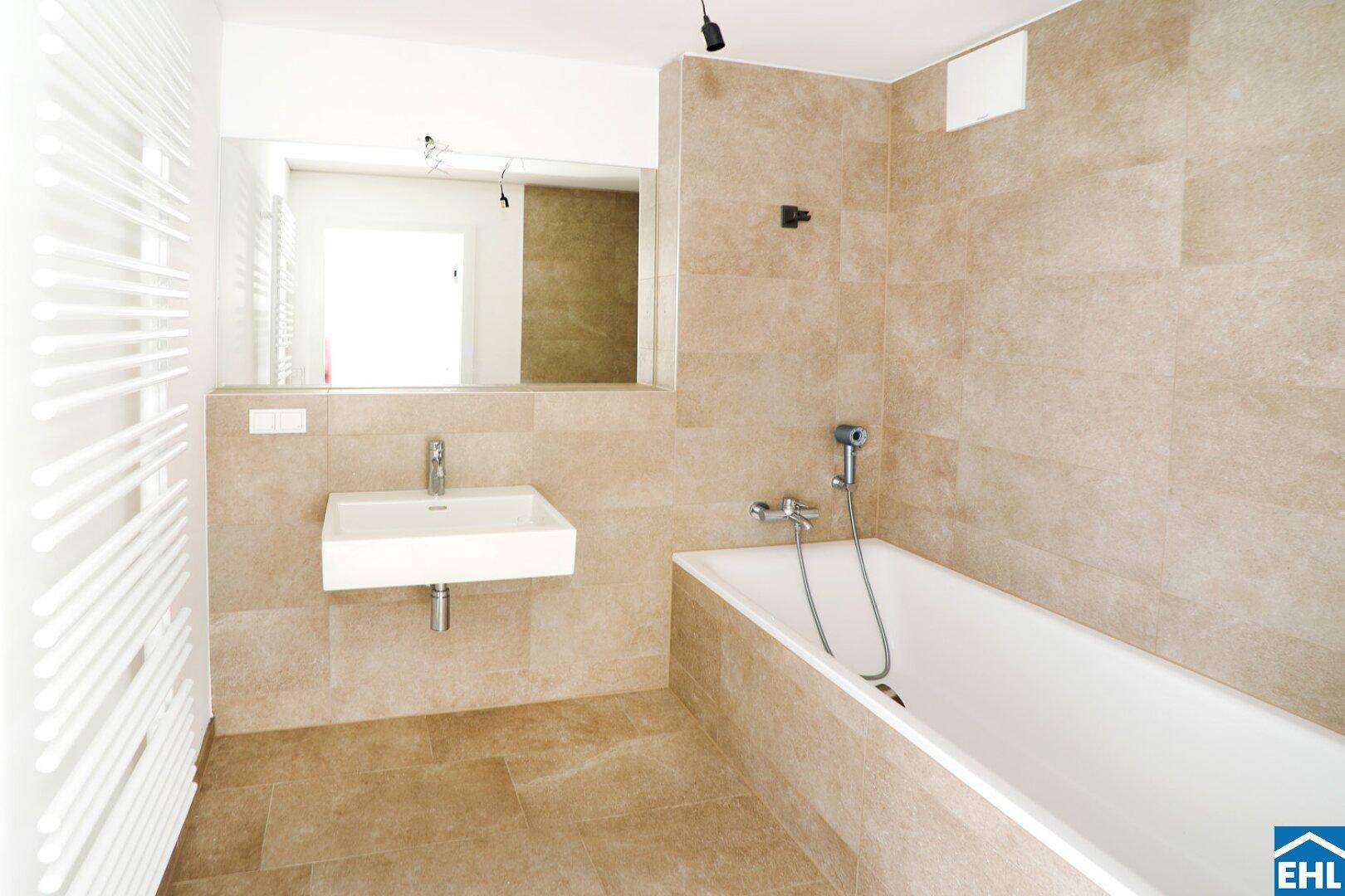 Modernes Badezimmer mit beigefarbenen Fliesen, Badewanne, Einzelwaschbecken und Handtuchheizkörper.
