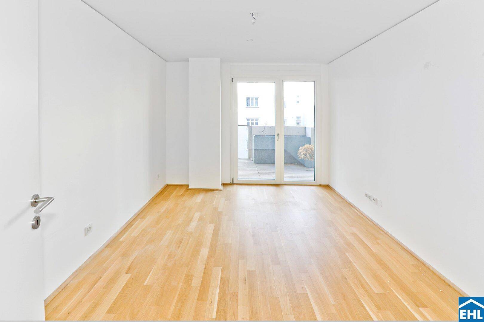 Geräumiges Schlafzimmer mit hellem Parkettboden und Zugang zu einem privaten Balkon.
