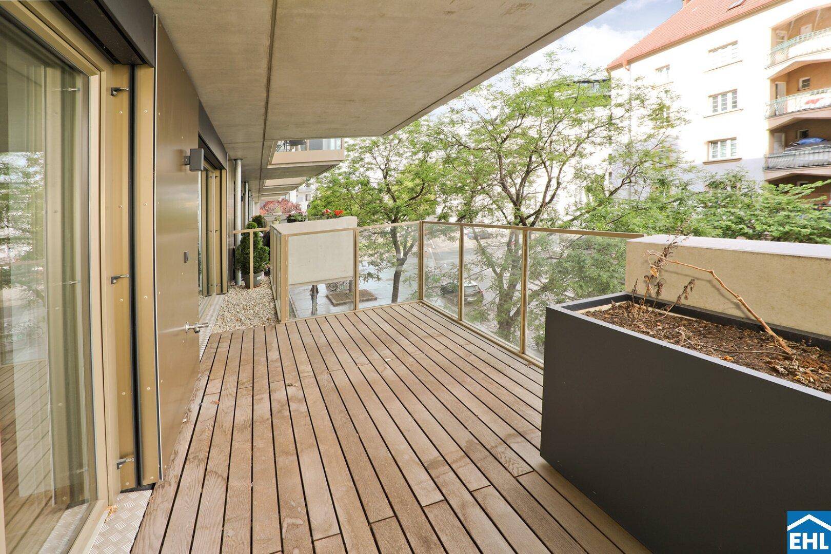 Moderner Balkon mit Holzdeck und Glasgeländer, ideal für entspannte Stunden im Freien.