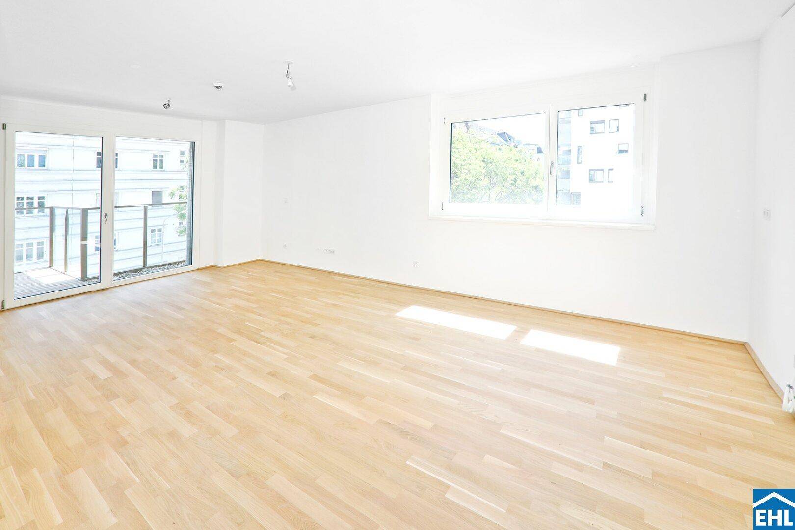 Geräumiger Wohnbereich mit hellem Holzfußboden und großen Fenstern für viel Tageslicht.