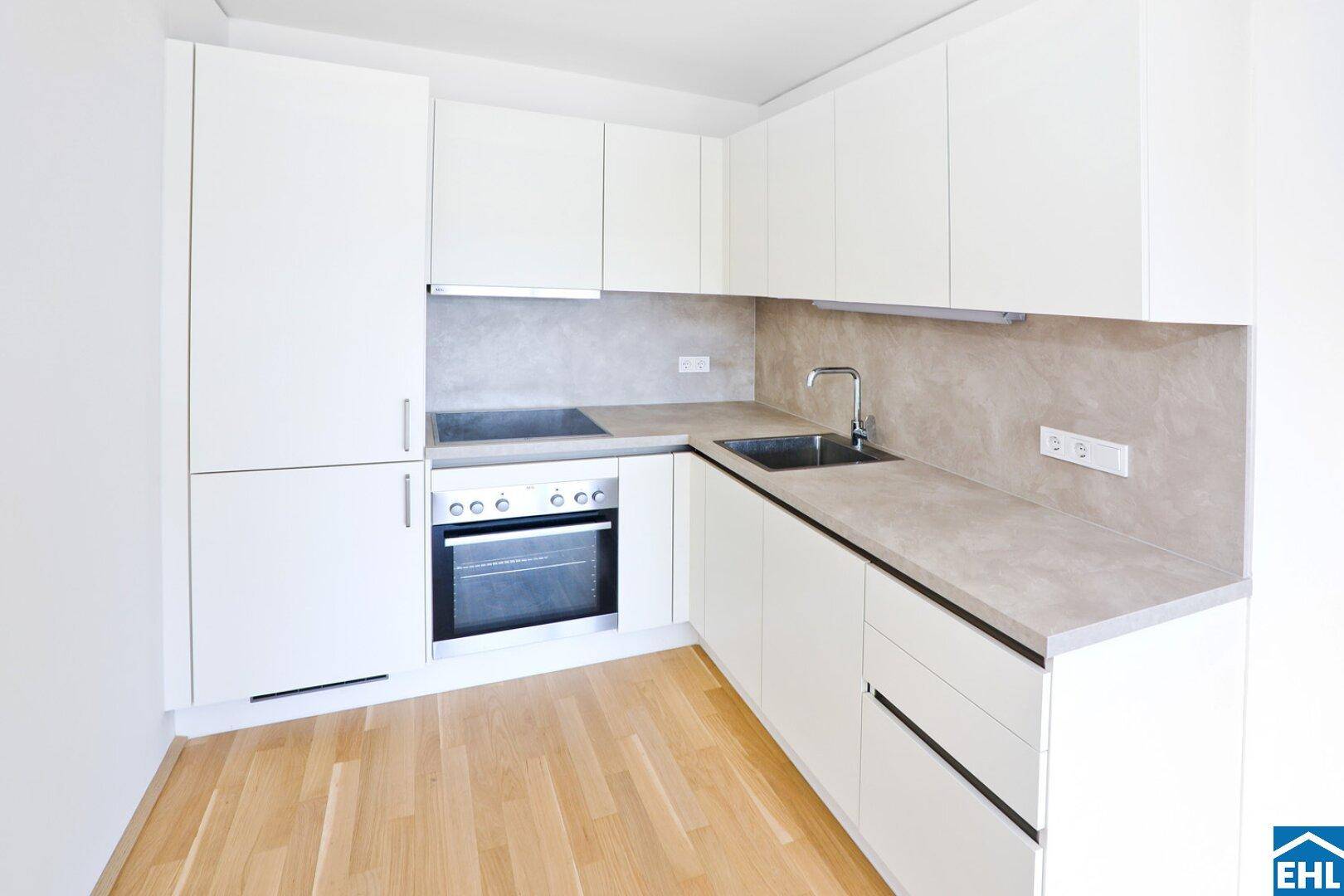 Moderne Einbauküche mit weißen Schränken, integriertem Backofen und Kochfeld.