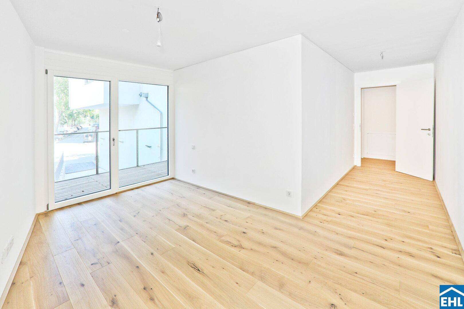 Heller Wohnraum mit Holzboden und Zugang zu einem Balkon, ideal für entspannte Stunden.