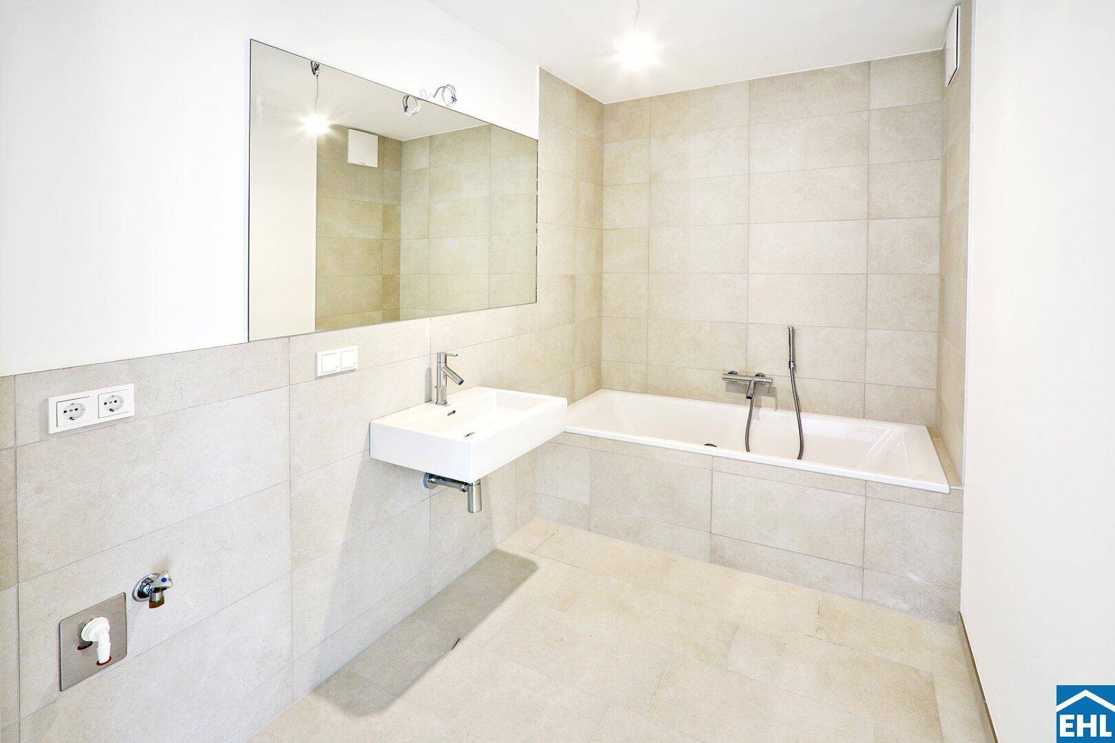 Modernes Badezimmer mit Badewanne, großem Spiegel und hellen Fliesen, schafft eine entspannende Atmosphäre.