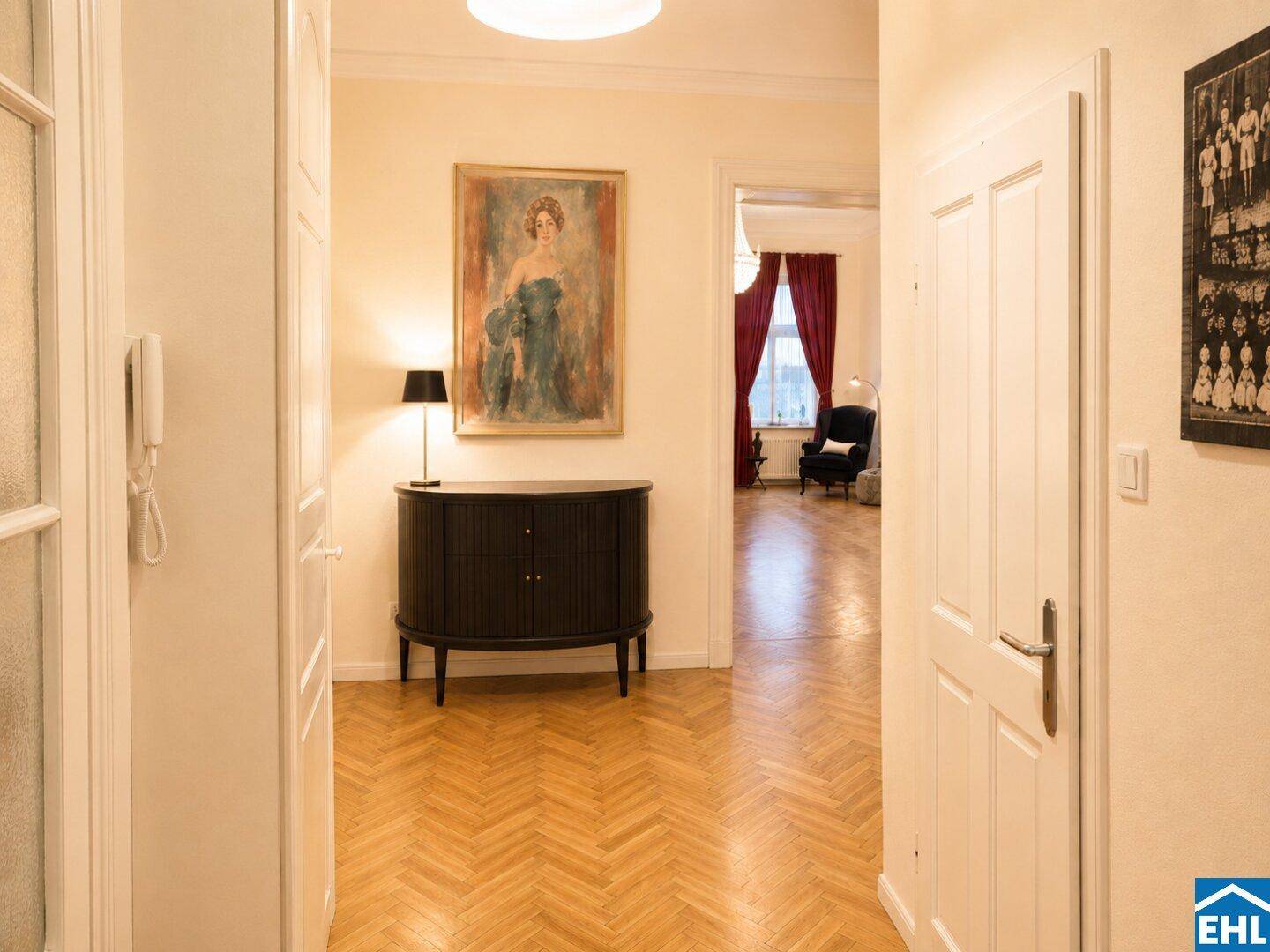 Eleganter Flur mit Fischgrätparkett, einer Kommode und einem Kunstwerk, das zum Schlafzimmer führt.
