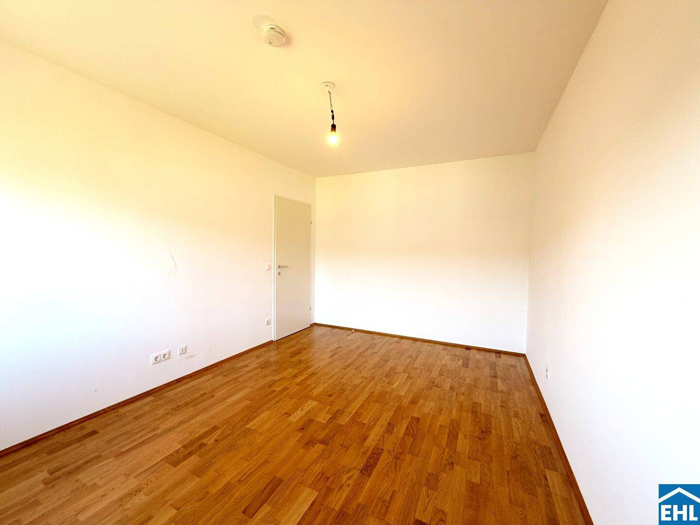 Geräumiges Schlafzimmer mit Parkettboden und weiß gestrichenen Wänden.
