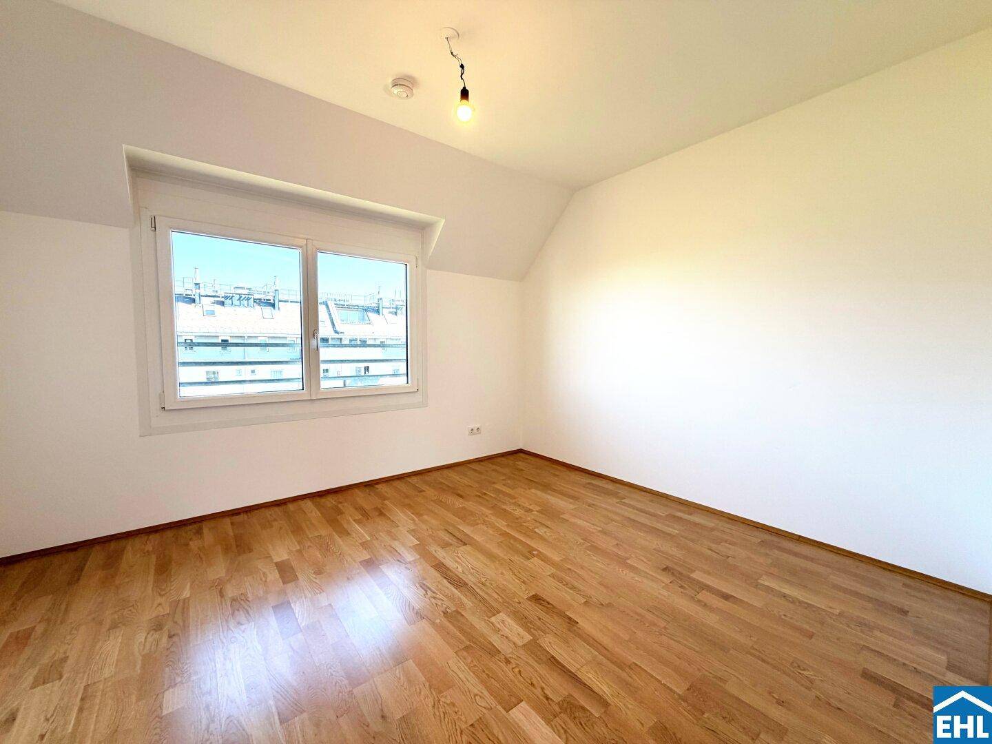 Freundliches Schlafzimmer mit Parkettboden, Fenster und Dachschräge.