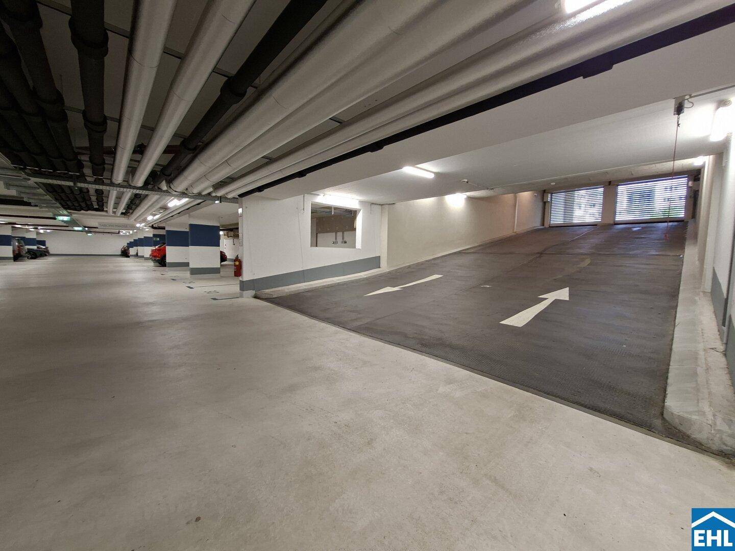 Geräumige Tiefgarage mit heller Beleuchtung, klaren Fahrbahnmarkierungen und einer Ausfahrtsrampe.