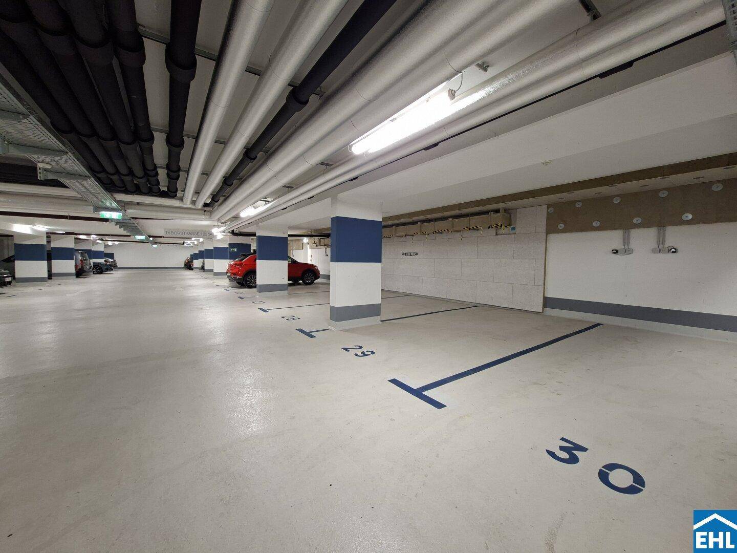 Saubere Tiefgarage mit nummerierten Stellplätzen und blauen Markierungen auf dem Betonboden.