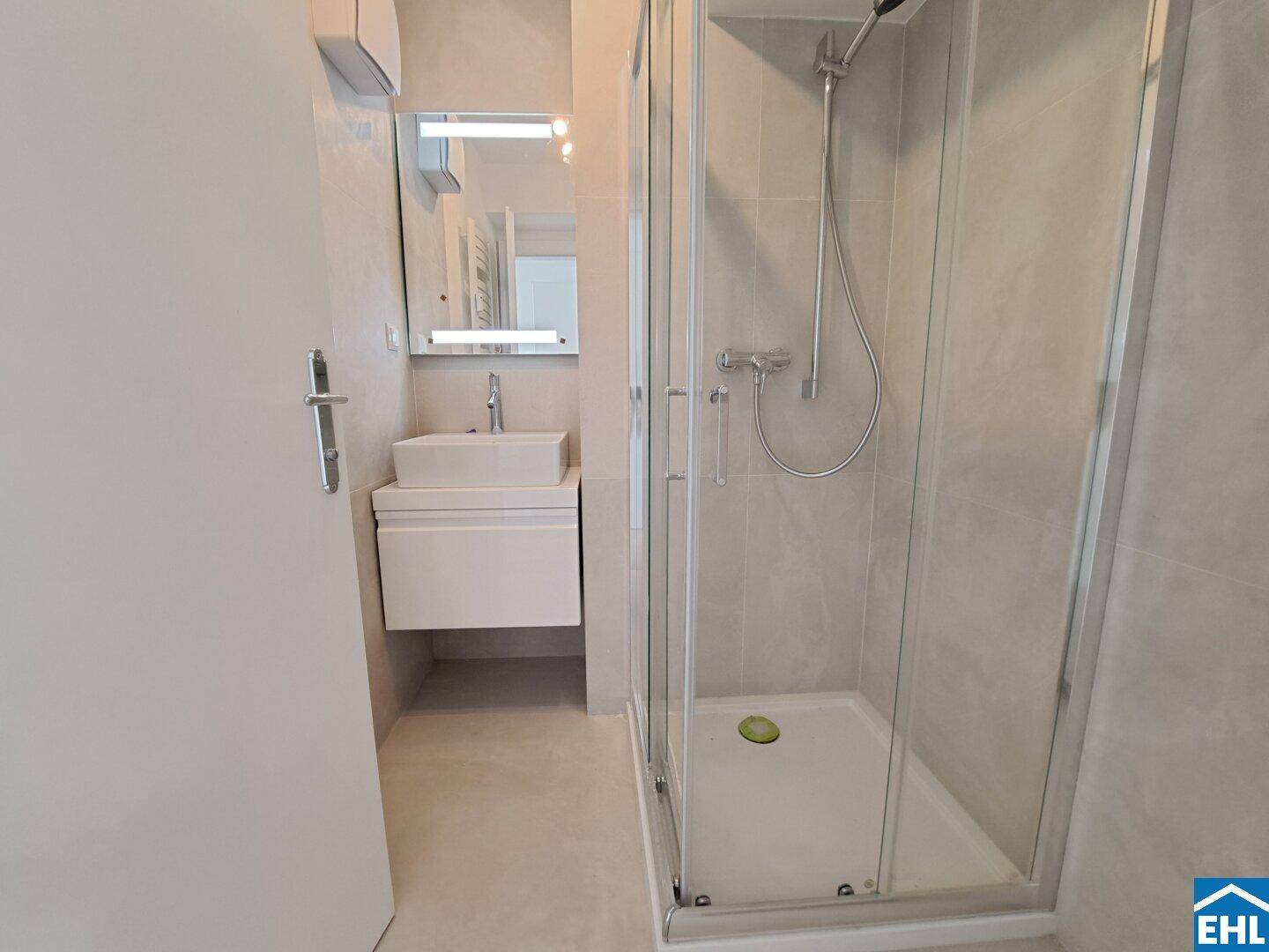 Modernes Badezimmer mit Duschkabine, Einzelwaschbecken und beheiztem Handtuchhalter.