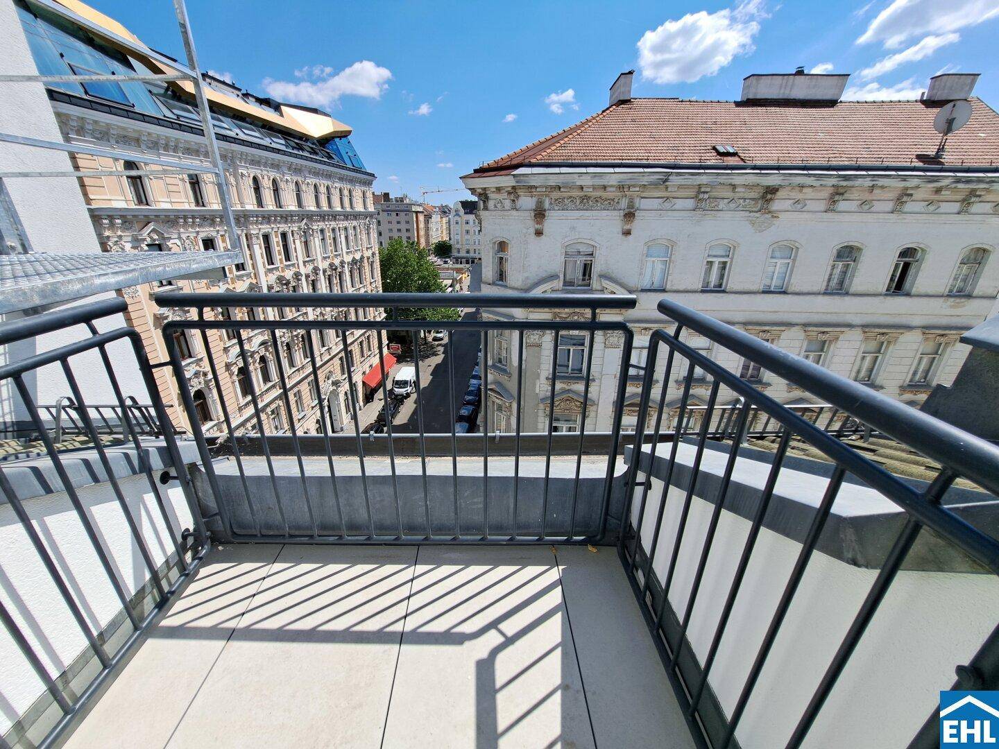 Geräumiger Balkon mit Fliesenboden und Metallgeländer, bietet einen weiten Stadtblick.
