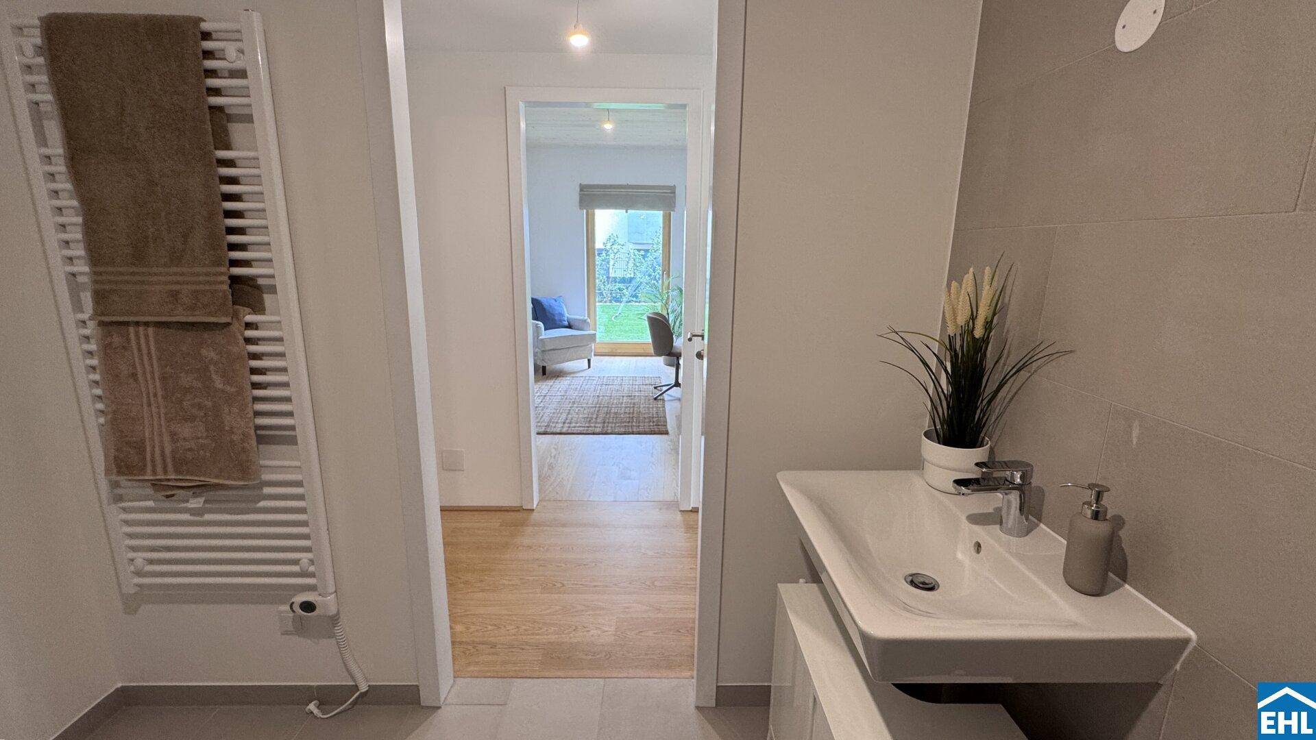 Badezimmer mit beheiztem Handtuchhalter und Blick in den angrenzenden Flur.