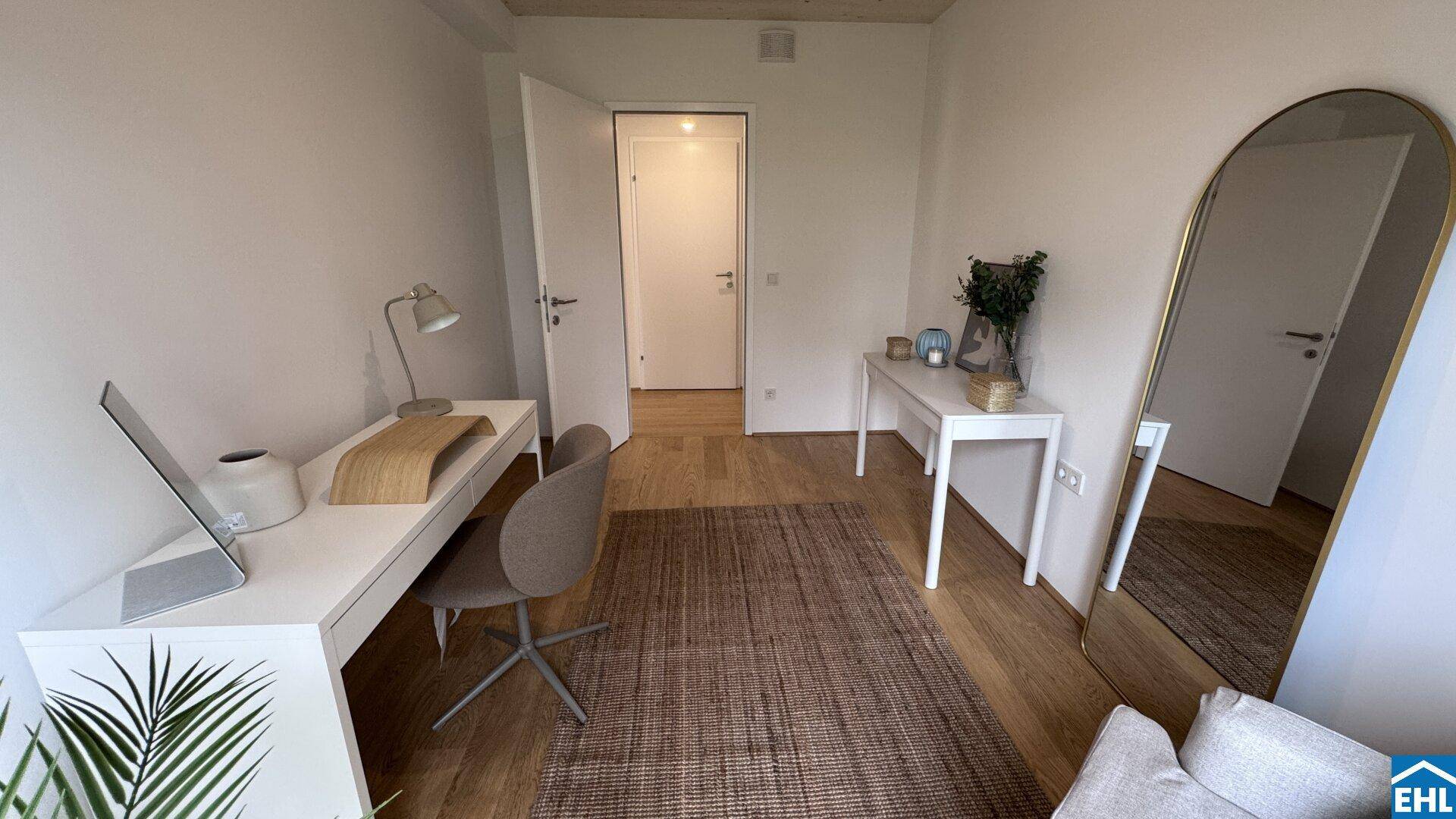 Helles Arbeitszimmer mit Holzboden, Schreibtisch und großem Spiegel.