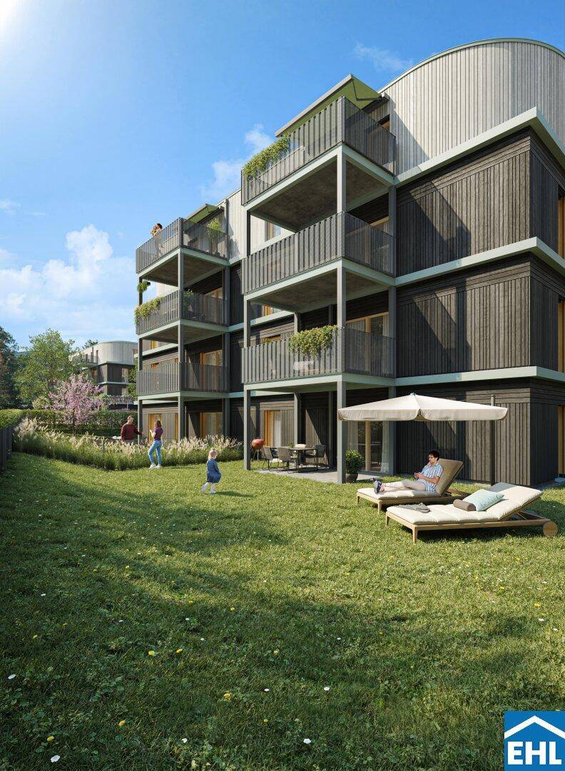 Gepflegte Gartenanlage mit Liegestühlen, Sonnenschirm und moderner Wohnanlage.