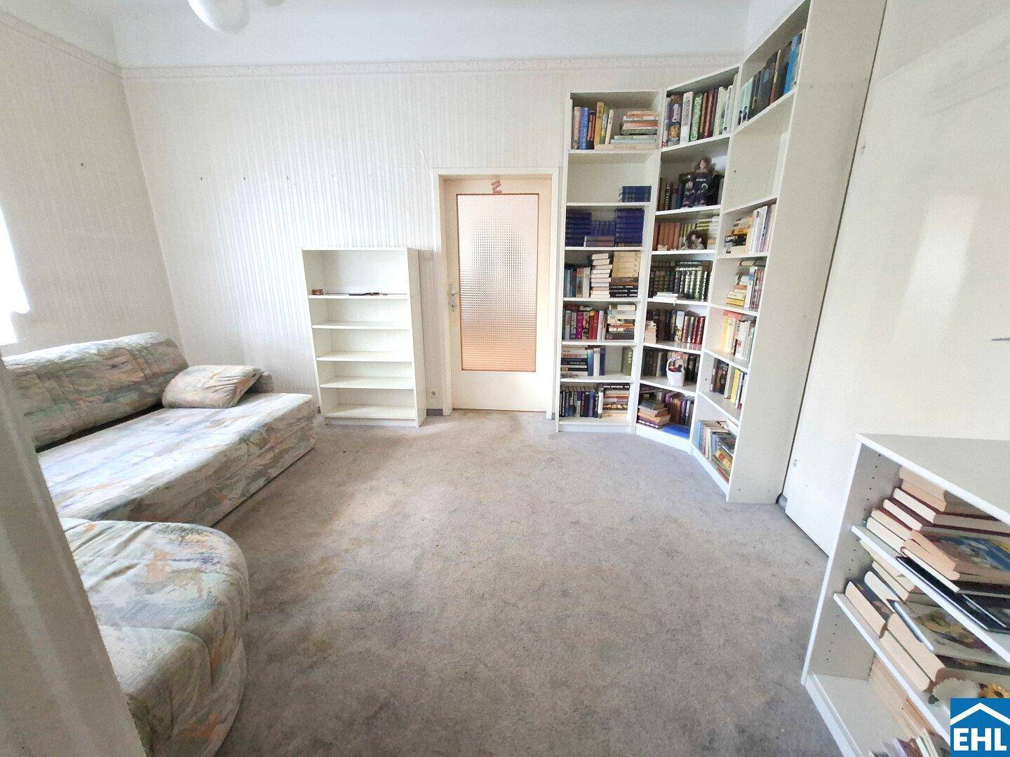 Zimmer mit Teppichboden und umfangreichen Bücherregalen, ideal als Arbeits- oder Lesezimmer.