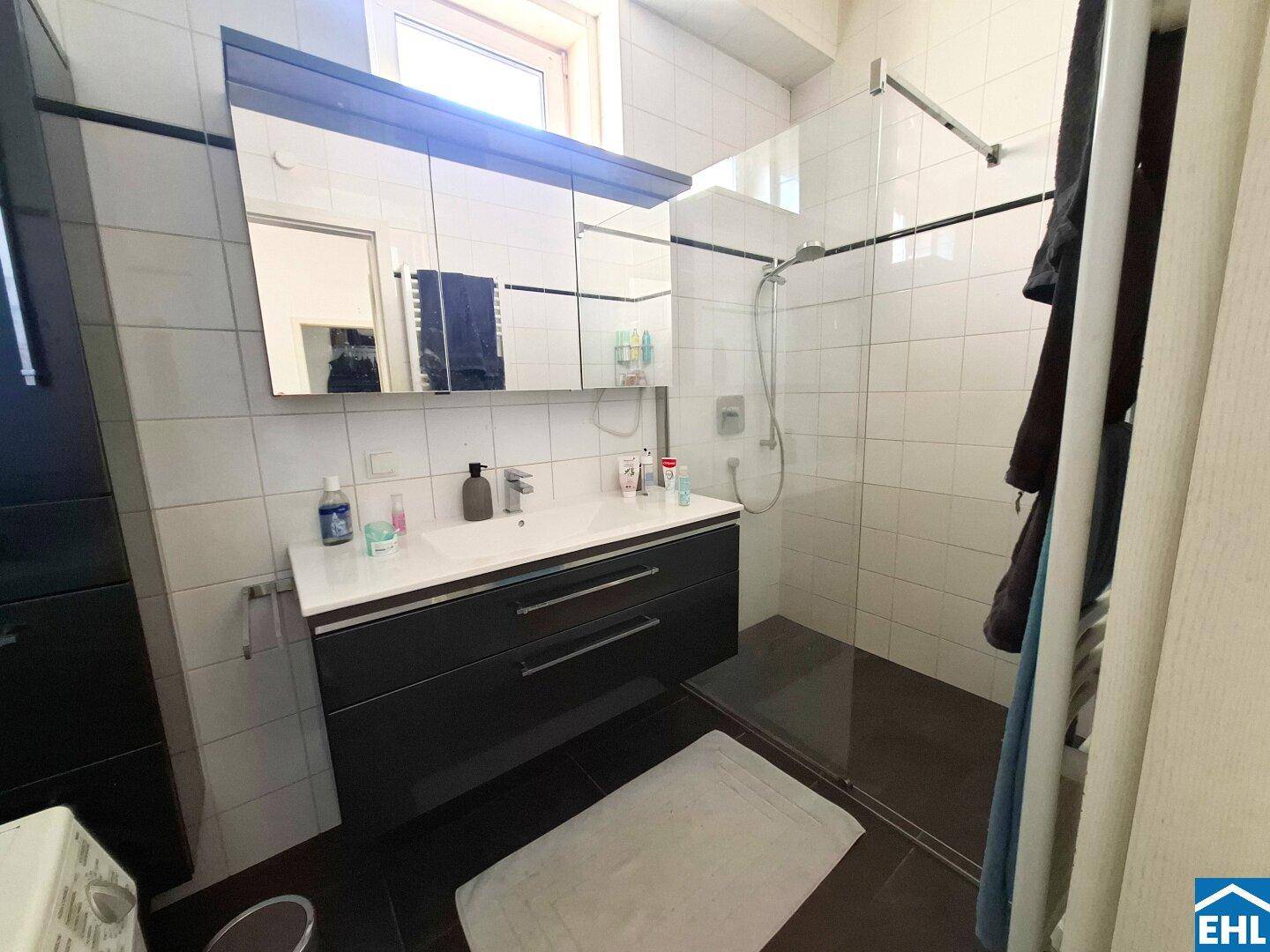 Modernes Badezimmer mit Duschkabine, großem Waschtisch und praktischem Spiegelschrank.