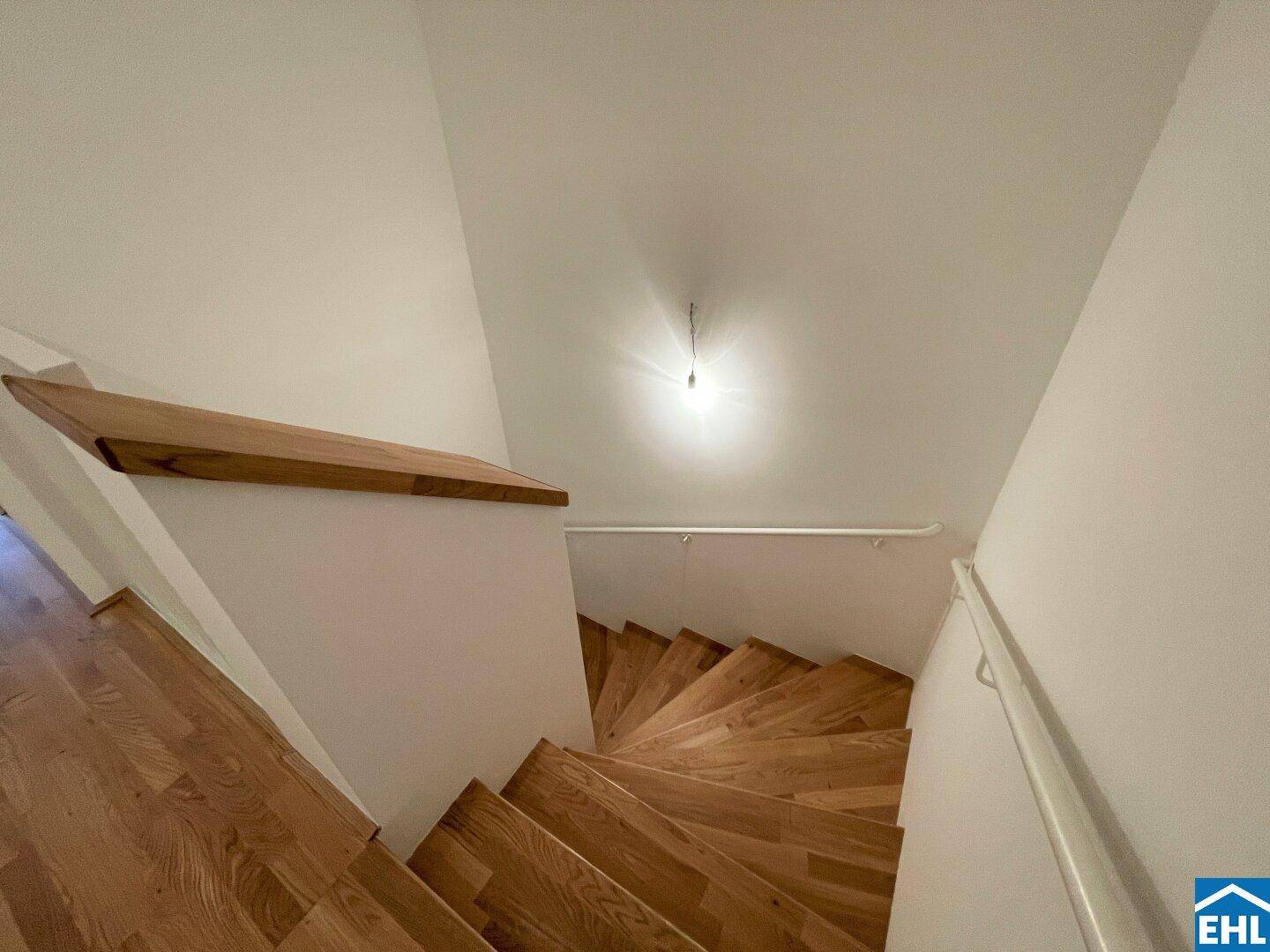 Holztreppe führt in die obere Etage, mit hellem Geländer und natürlichem Lichteinfall.