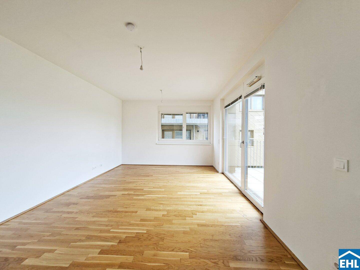 Geräumiges, helles Wohnzimmer mit Parkettboden und großen Fenstern, bereit zur individuellen Gestaltung.