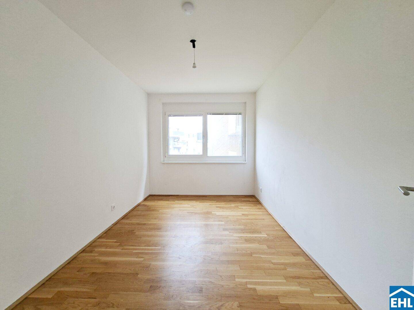 Helles Schlafzimmer mit Parkettboden und Fenster, ideal für Ruhe und Entspannung.