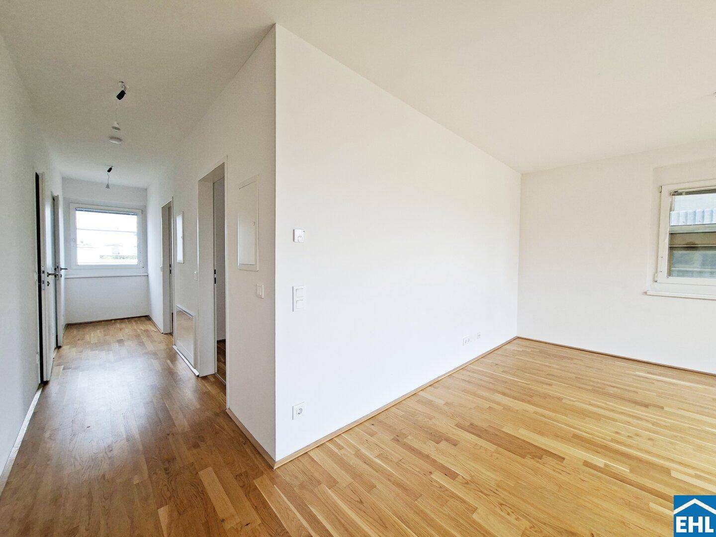 Heller Flur mit Parkettboden, der zu den verschiedenen Räumen der Wohnung führt.