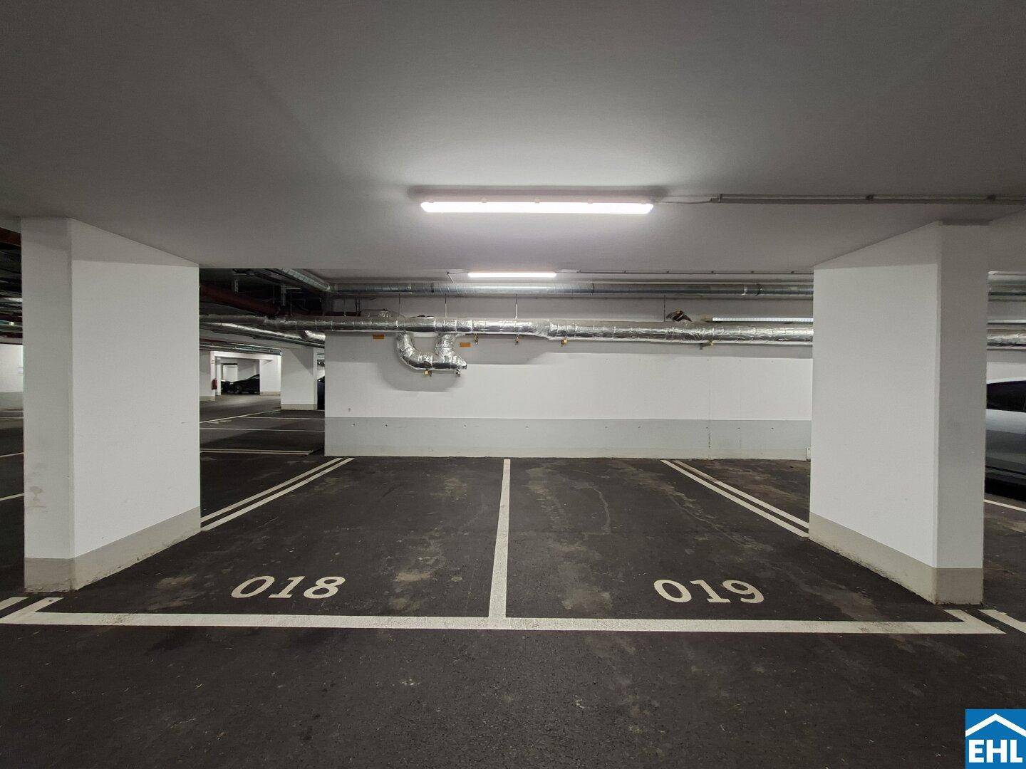 Zwei markierte Parkplätze in einer sauberen Tiefgarage mit Säulen und Deckenbeleuchtung.