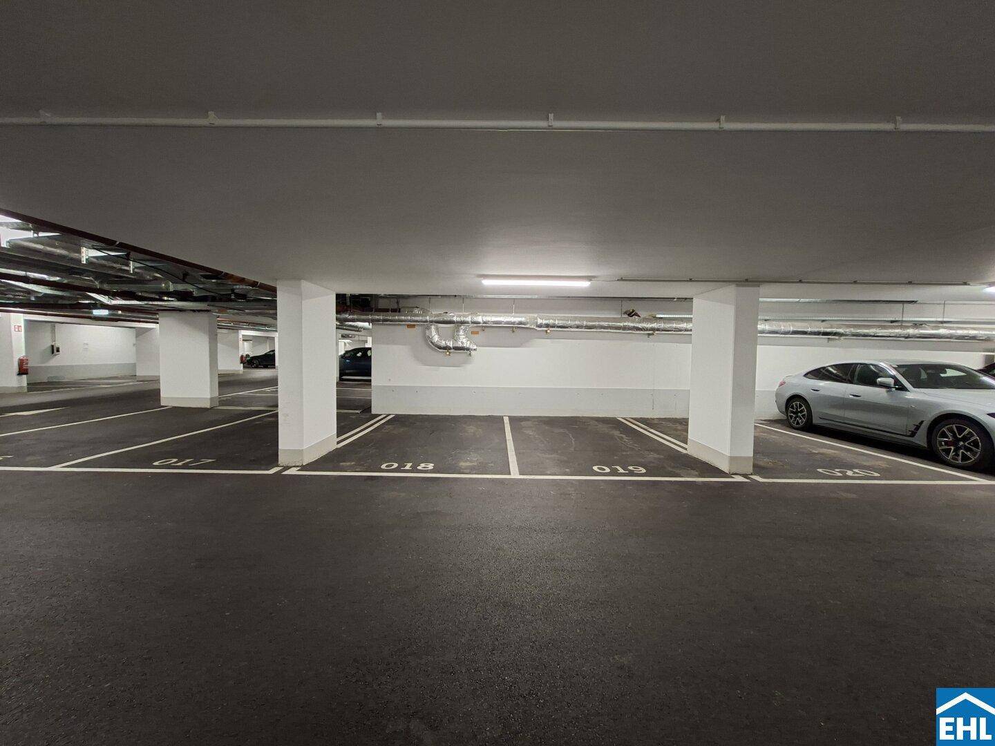 Reihe von Parkplätzen in einer Tiefgarage, teilweise belegt, mit klarer Beschilderung und guter Beleuchtung.