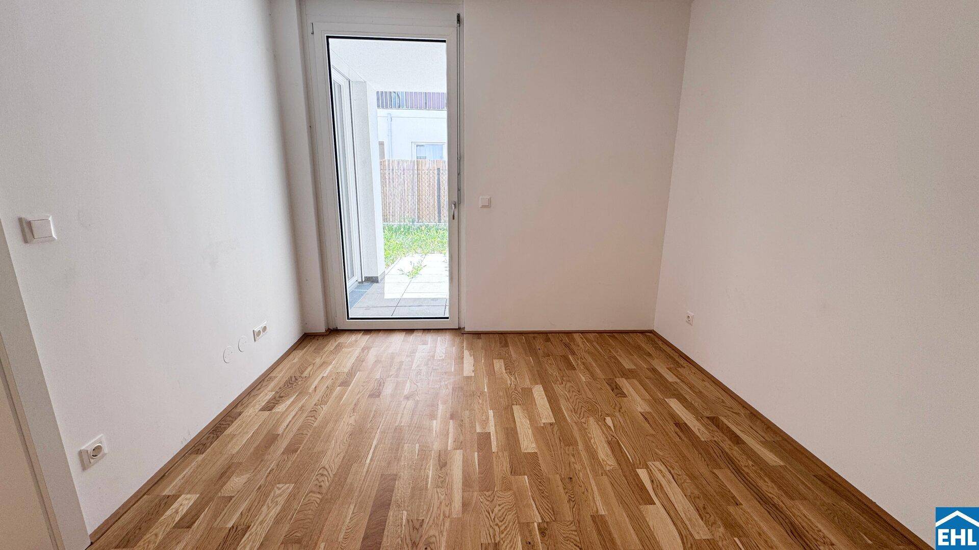 Helles Zimmer mit Holzboden und Zugang zu einer Terrasse, ideal als Schlaf- oder Arbeitszimmer.