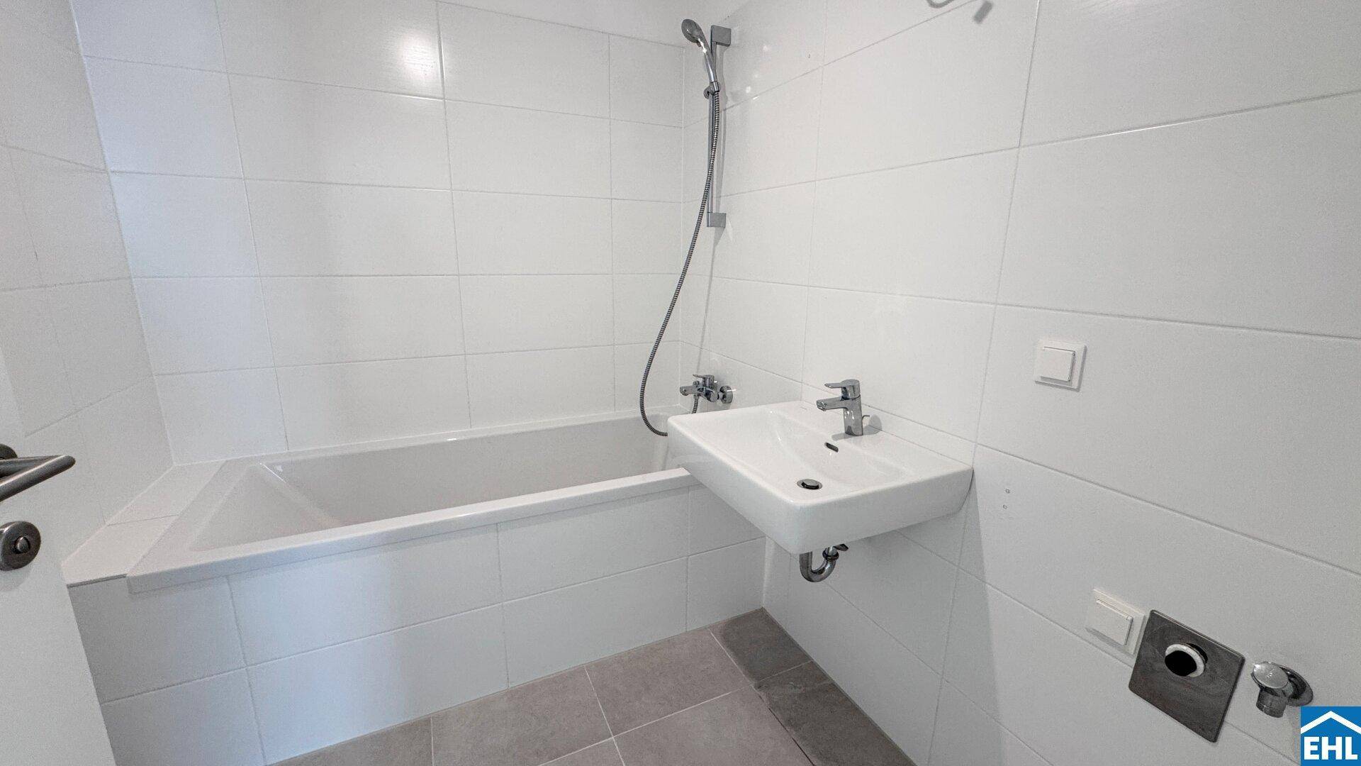 Modernes Badezimmer mit Badewanne, Waschbecken und weißen Fliesen, in gutem Zustand.