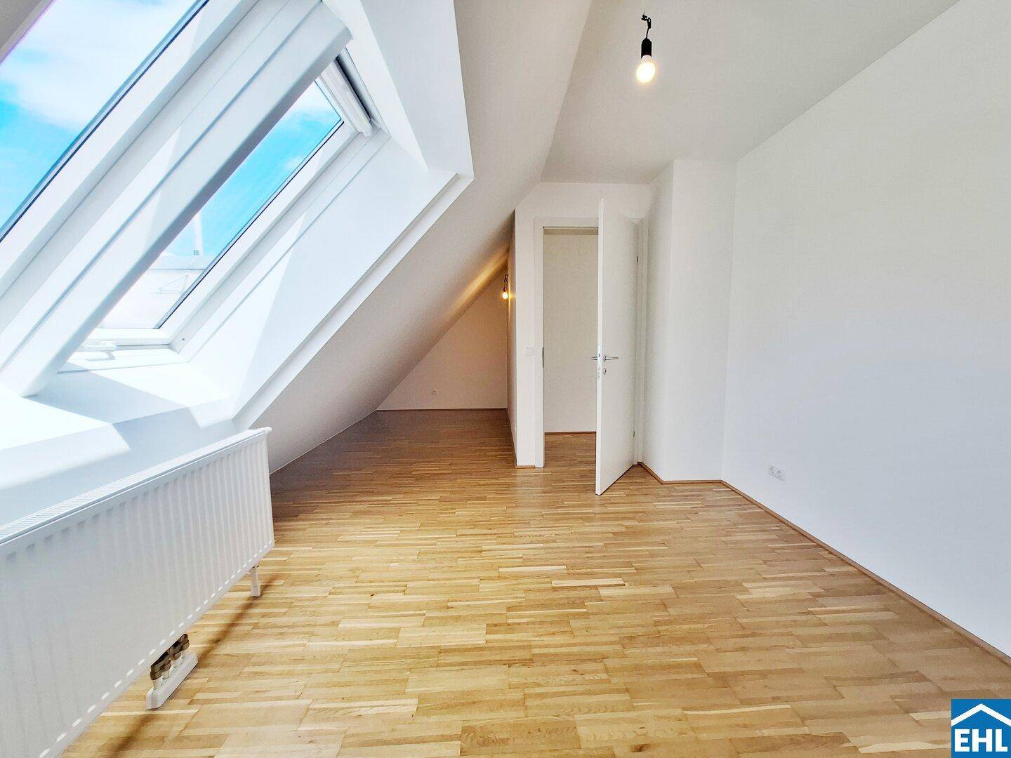 Dachzimmer mit Parkettboden und schrägen Wänden, bietet eine gemütliche Atmosphäre.