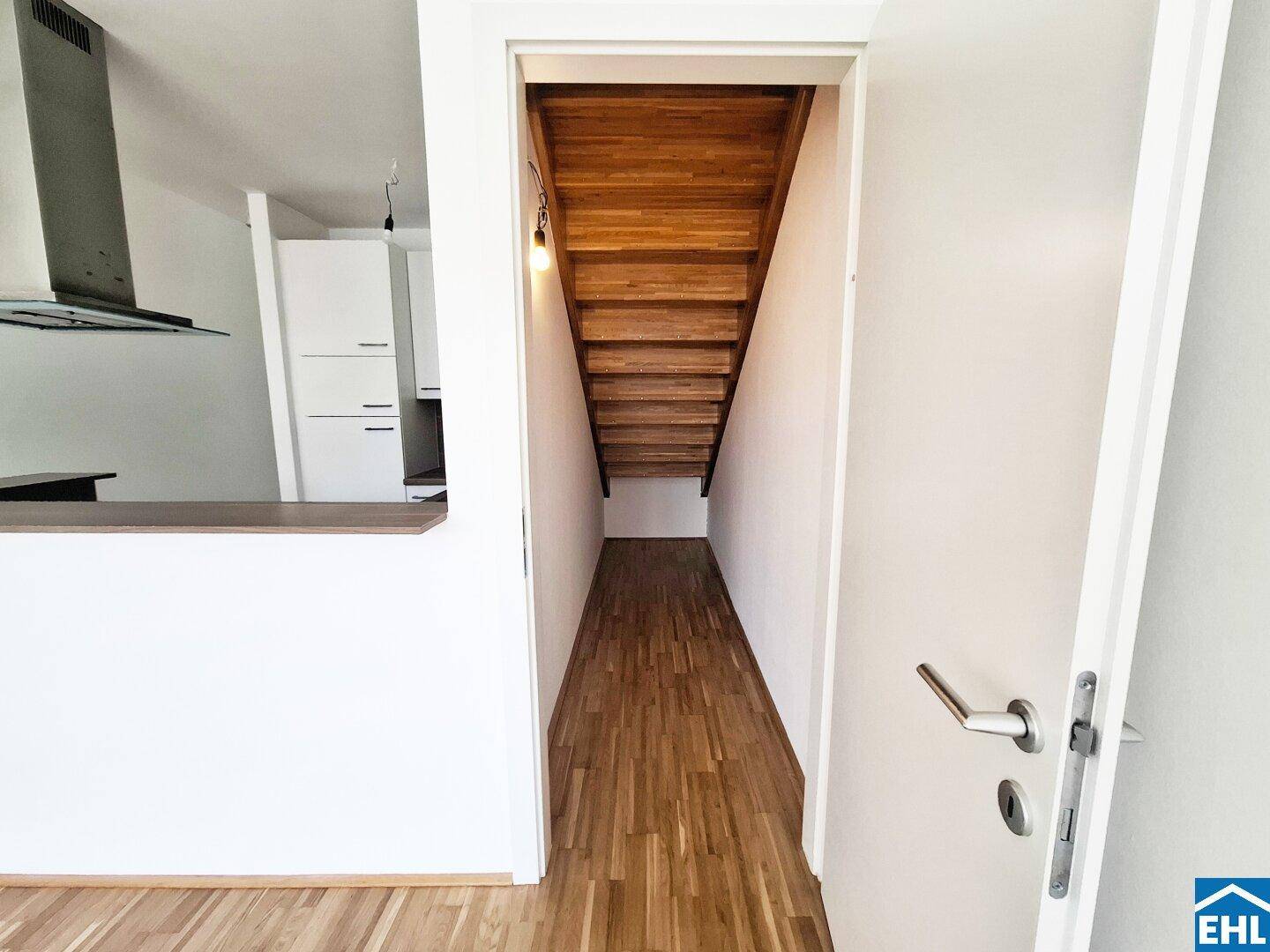 Eingangsbereich mit Holztreppe, die in die obere Etage führt, und Parkettboden.