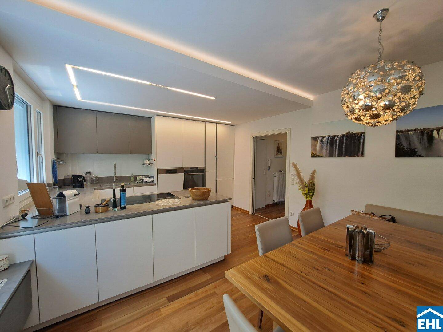 Moderne Küche mit Kochinsel und Essbereich, ausgestattet mit einem großen Holztisch.