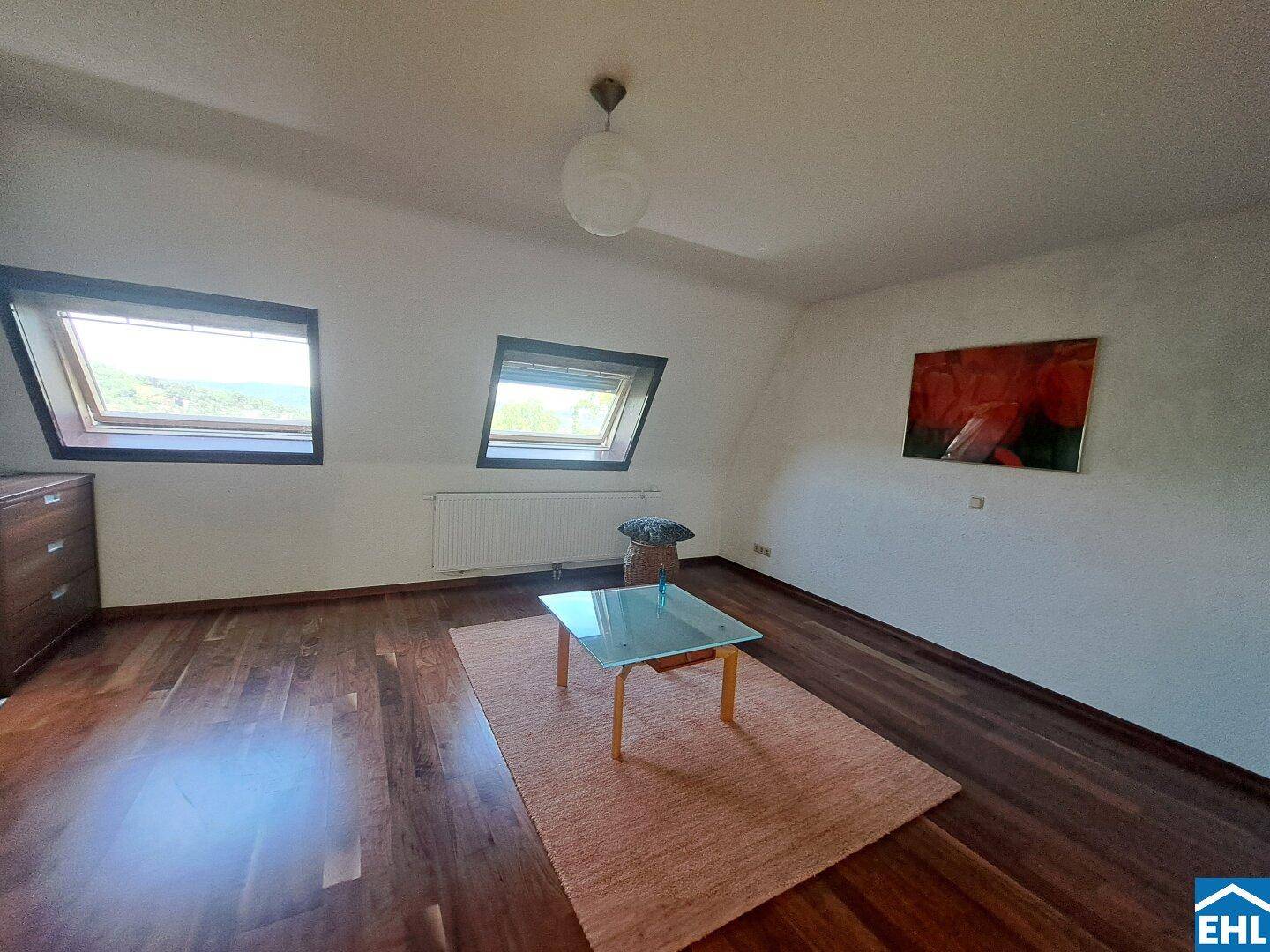 Dachzimmer mit Holzboden, zwei Dachfenstern und schräger Decke, bietet viel Licht.