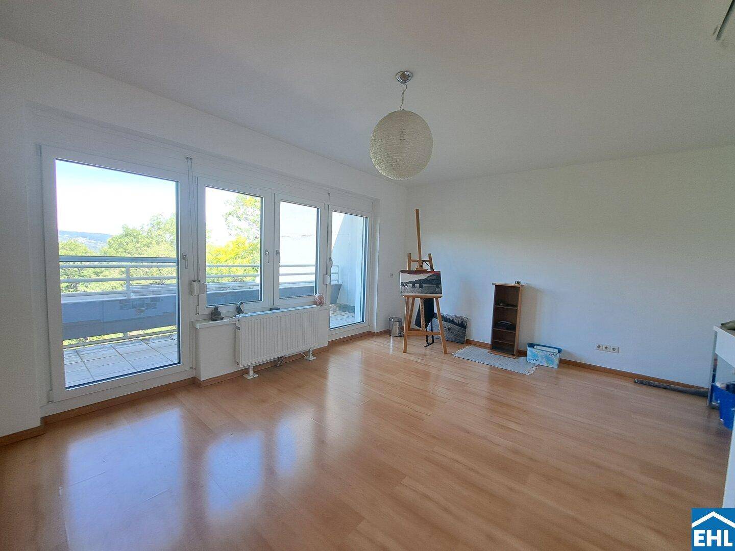 Geräumiges Zimmer mit Laminatboden und großen Fenstern, die viel Tageslicht hereinlassen.