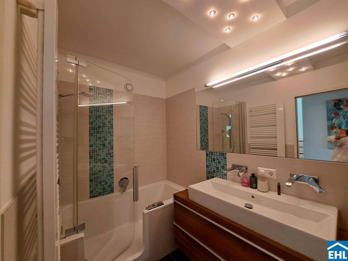 Modernes Badezimmer mit Badewanne, Dusche, Doppelwaschbecken und beheiztem Handtuchhalter.