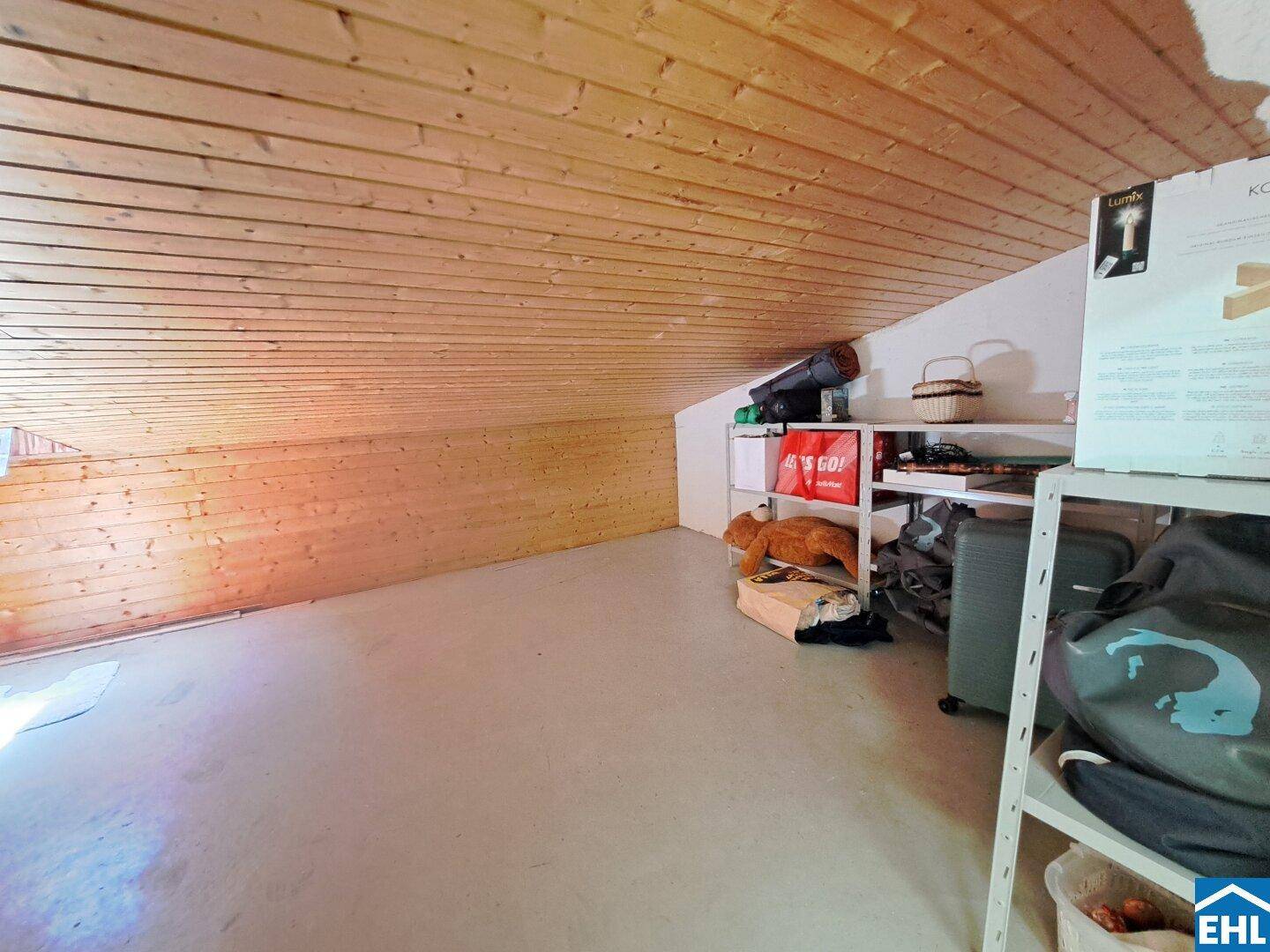 Geräumiger Dachboden als Abstellraum mit Holzverkleidung und schräger Decke.