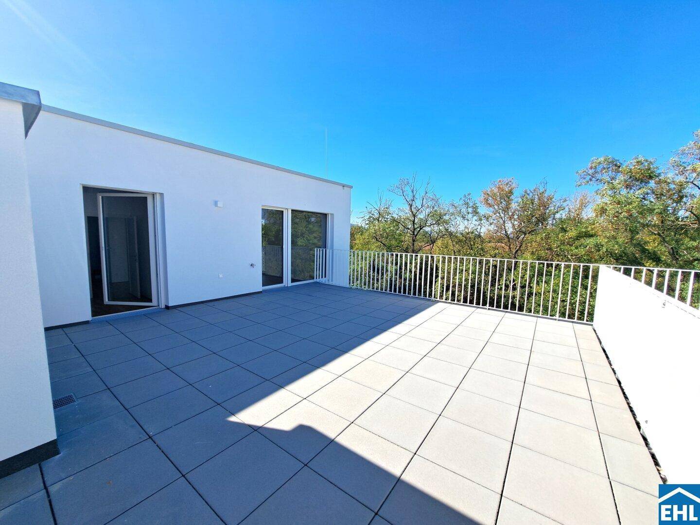 Weitläufige Dachterrasse mit modernen Fliesen und Blick auf die umliegende grüne Landschaft.