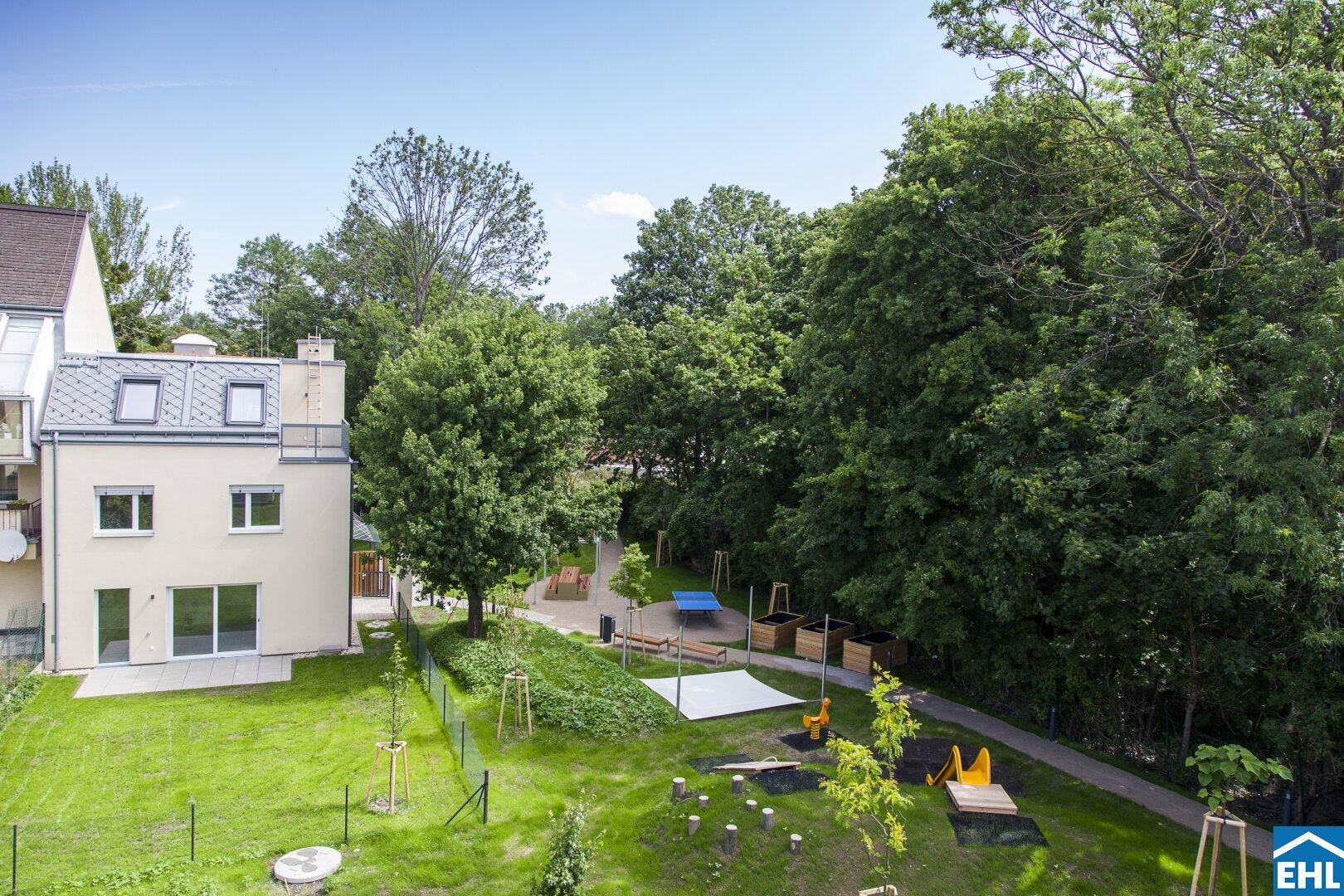Blick auf die Wohnanlage mit großem Gemeinschaftsgarten und vielfältigen Spielmöglichkeiten für Kinder.