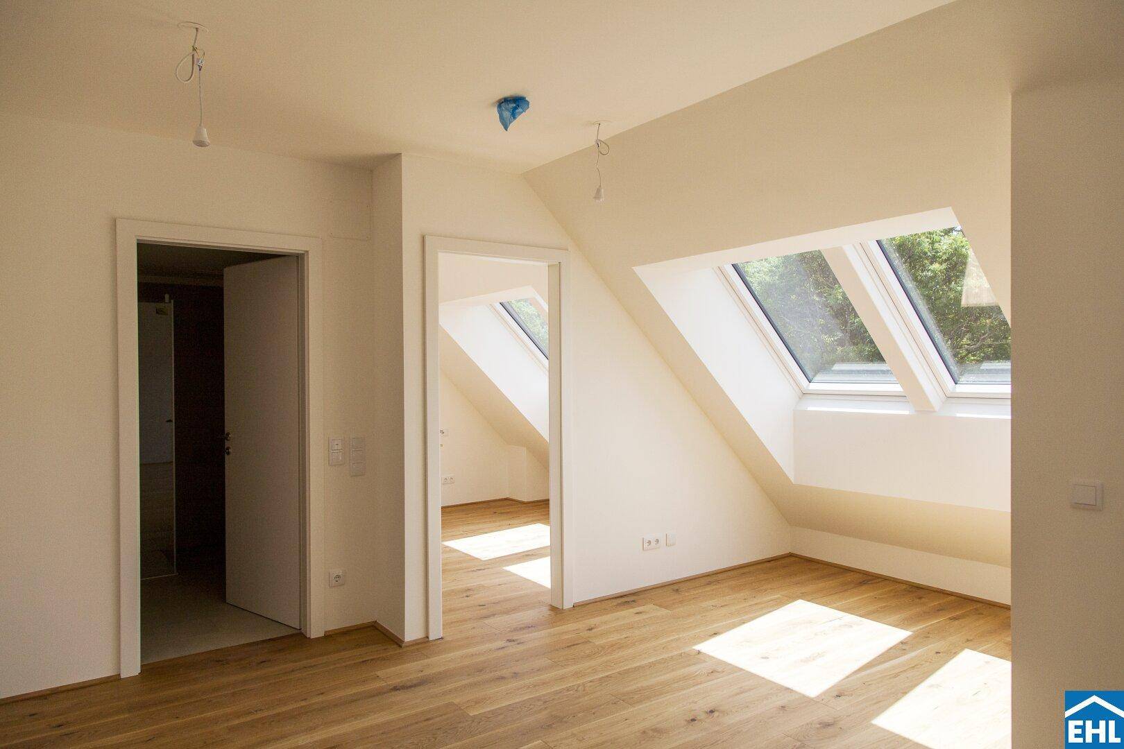 Schlafzimmer mit Holzboden und mehreren Dachfenstern, die viel Tageslicht hereinlassen.