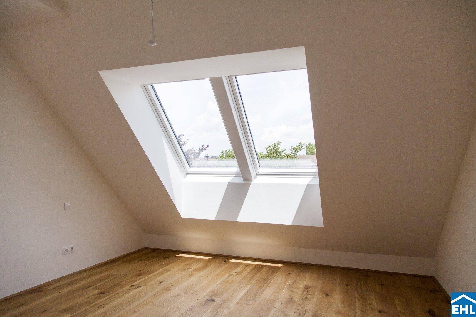 Helles Schlafzimmer im Dachgeschoss mit schrägen Wänden und zwei großen Dachfenstern.