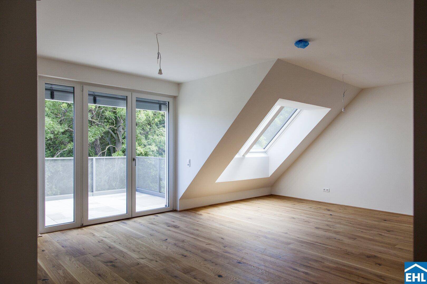 Geräumiger Wohnbereich mit Holzboden, Balkonzugang und schrägem Dachfenster.